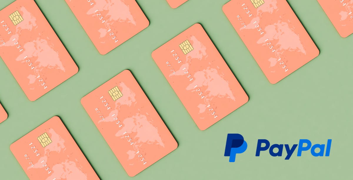 Sage green background with salmon pink credit cards with world map on the upper left corner, PayPal logo in bottom right corner. 