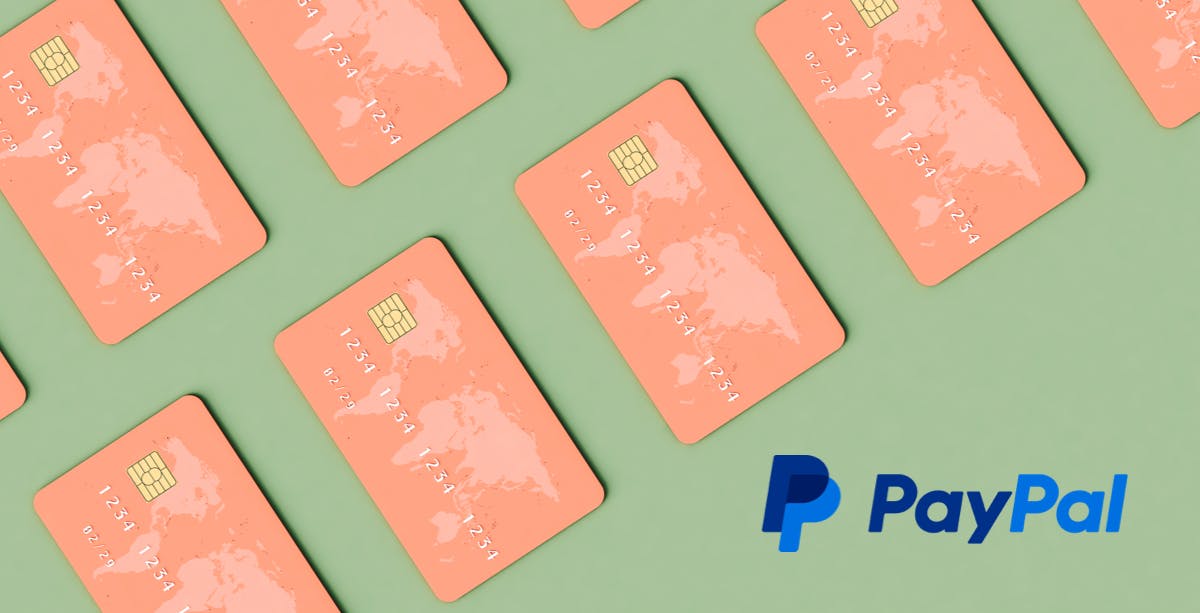 Sage green background with salmon pink credit cards with world map on the upper left corner, PayPal logo in bottom right corner.
