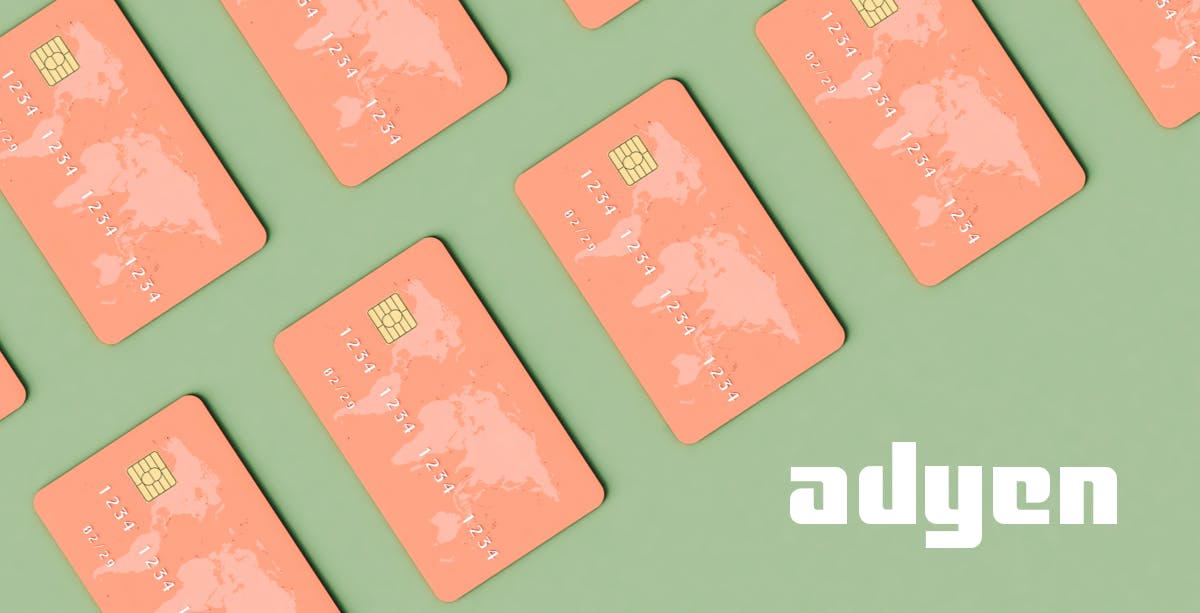Sage green background with salmon pink credit cards with world map on the upper left corner, Adyen logo in bottom right corner. 
