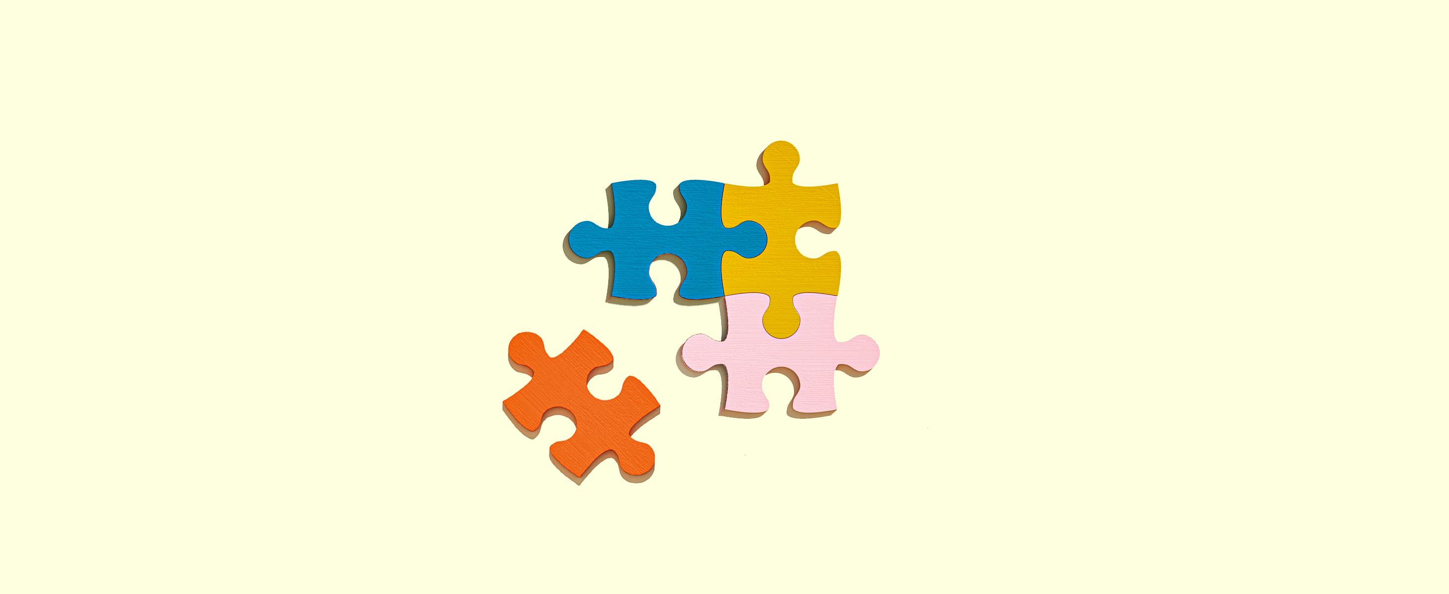Four puzzle pieces in different colors on a pale yellow background. Three pieces are together, a red piece is loose but clearly fits the other three pieces to complete a square.