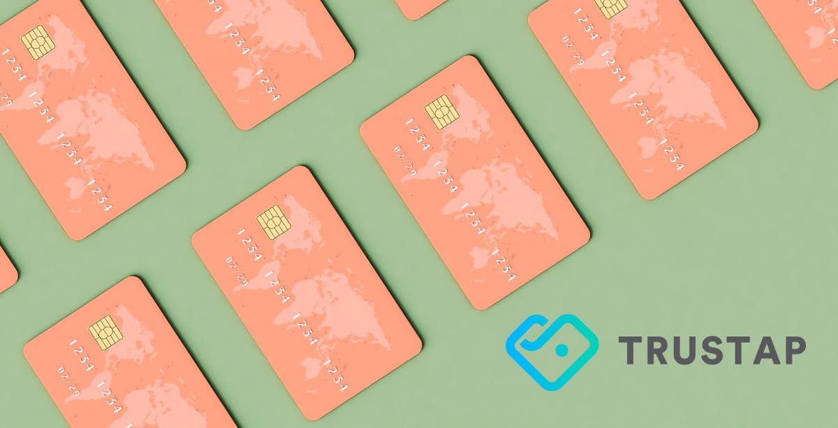 Sage green background with salmon pink credit cards with world map on the upper left corner, blue and gray Trystao logo in bottom right corner.