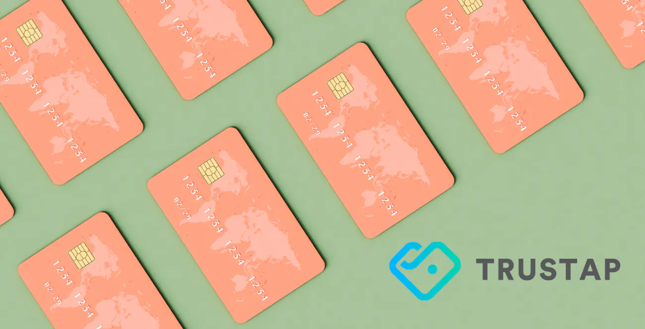 Sage green background with salmon pink credit cards with world map on the upper left corner, blue and gray Trystao logo in bottom right corner.