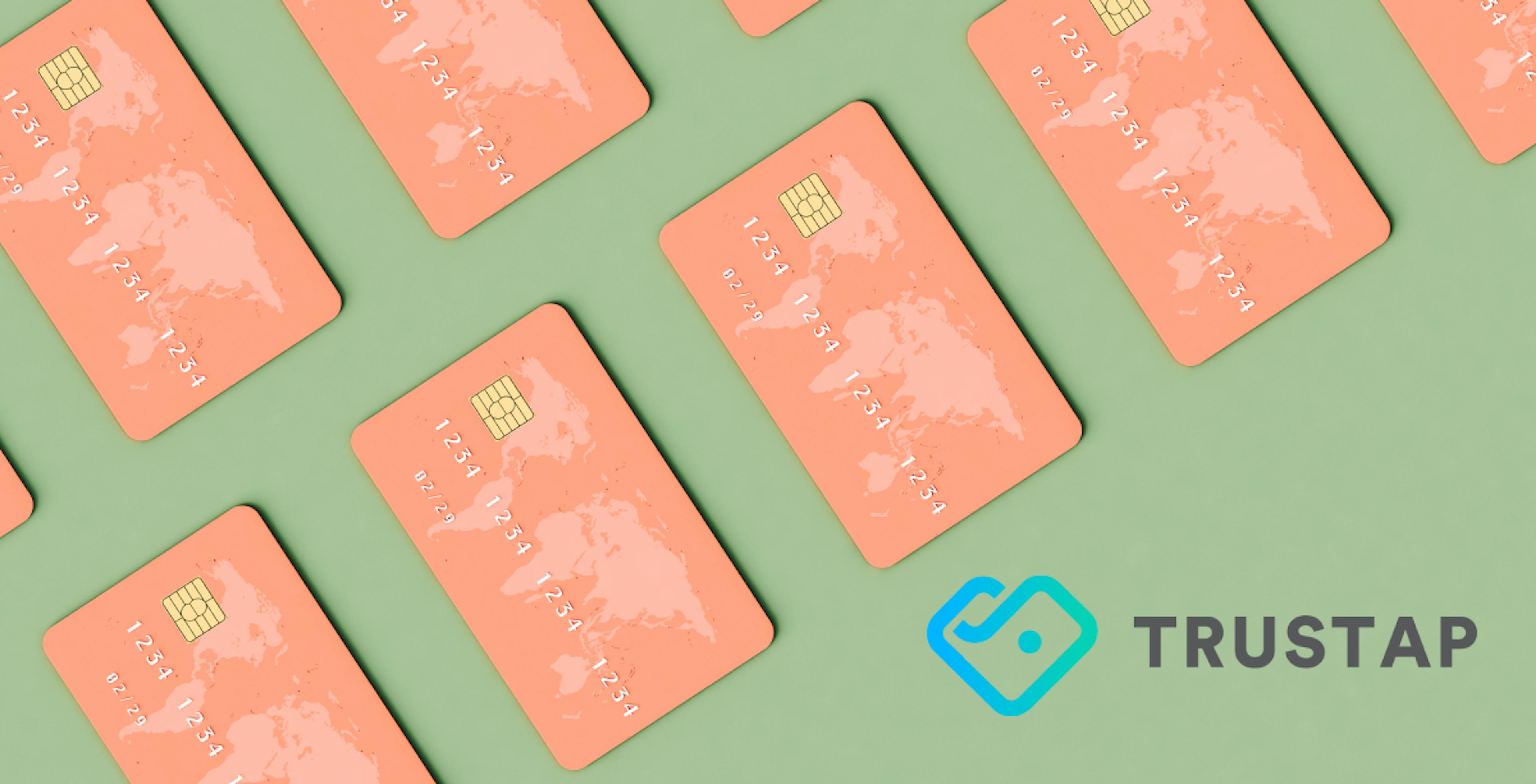 Sage green background with salmon pink credit cards with world map on the upper left corner, blue and gray Trystao logo in bottom right corner.