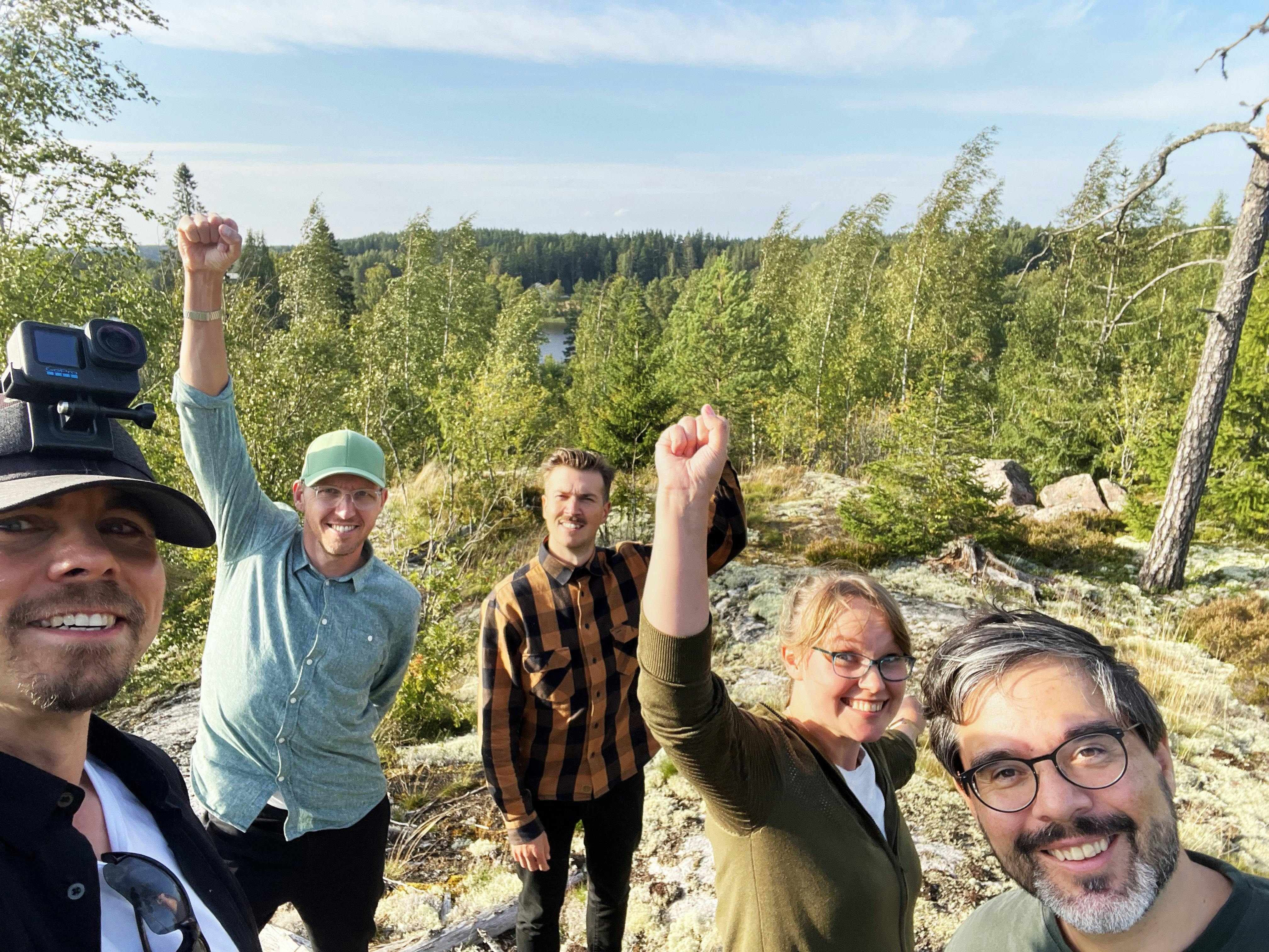 Five people hiking in a forest, smiling.