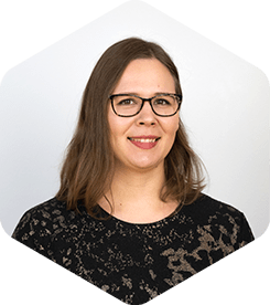 Jenni is smiling at the camera. She's wearing a black shirt with flower patterns and black-rimmed glasses.