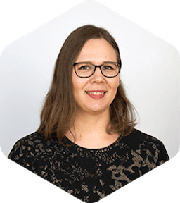 Jenni is smiling at the camera. She's wearing a black shirt with flower patterns and black-rimmed glasses.