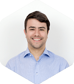 Luis is smiling widely at the camera. He has a light-blue shirt on with the top-most button open for a relaxed vibe.