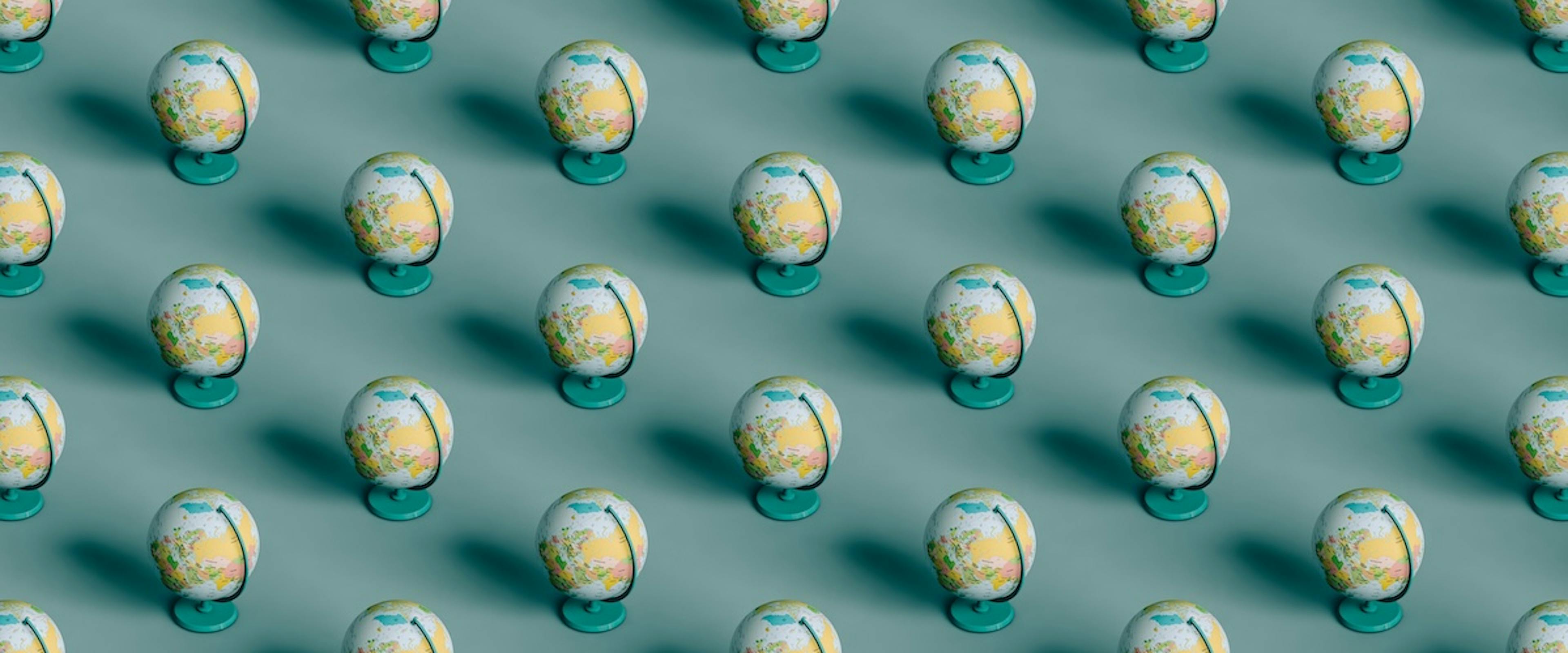 3d pattern of many globes on turquoise-blue background.