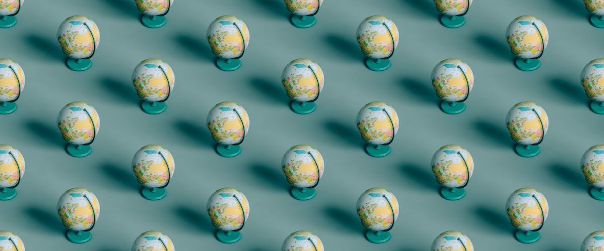 3d pattern of many globes on turquoise-blue background.