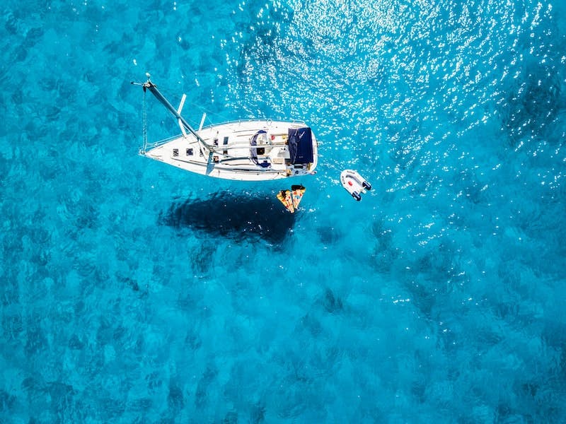 A birds-eye view of a yacht on clear water. Photo by Robert H on Unsplash.