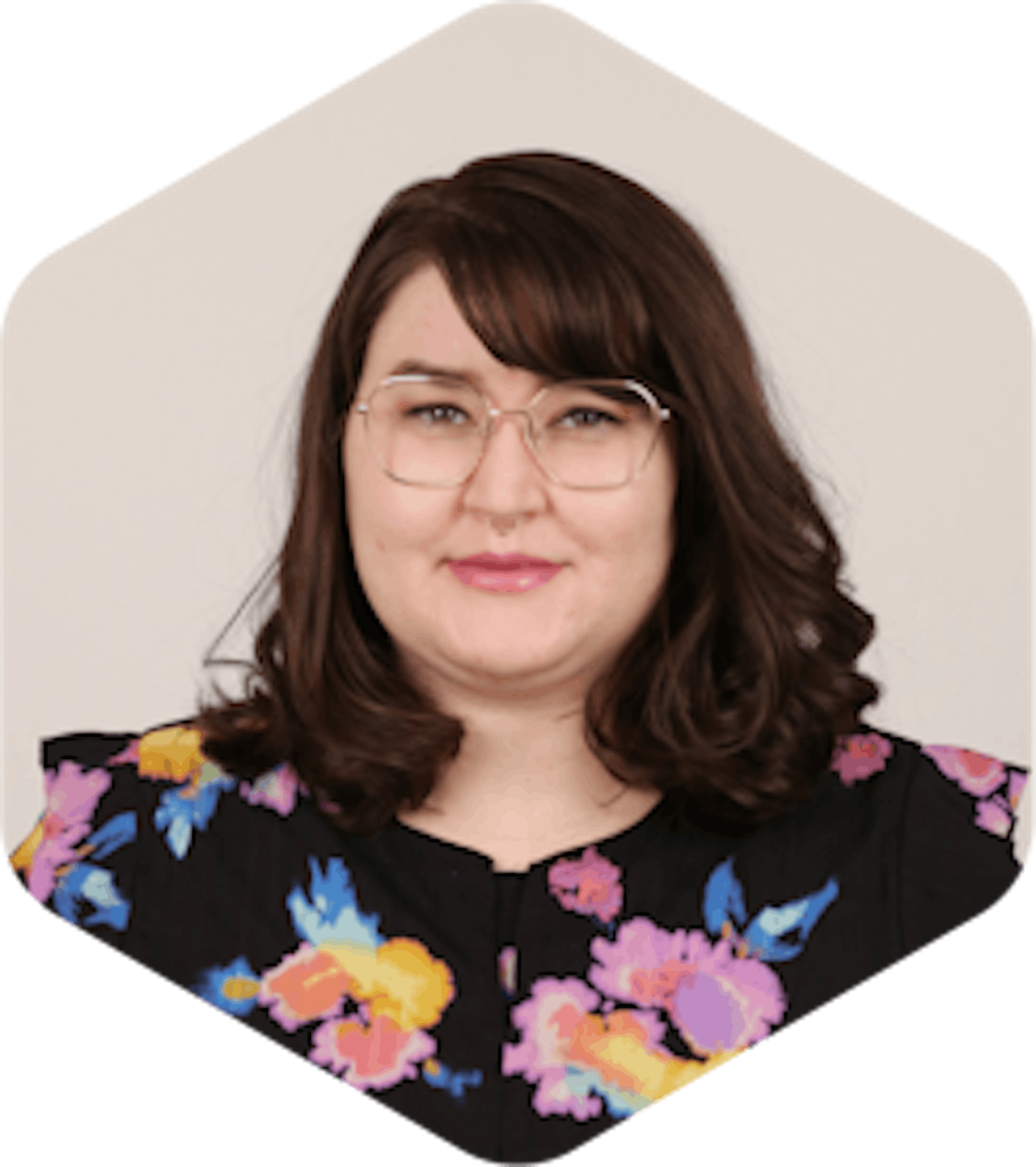Amanda has dark, medium-lengthed brown hair, glasses, and a black floral shirt. She is smiling at the camera.