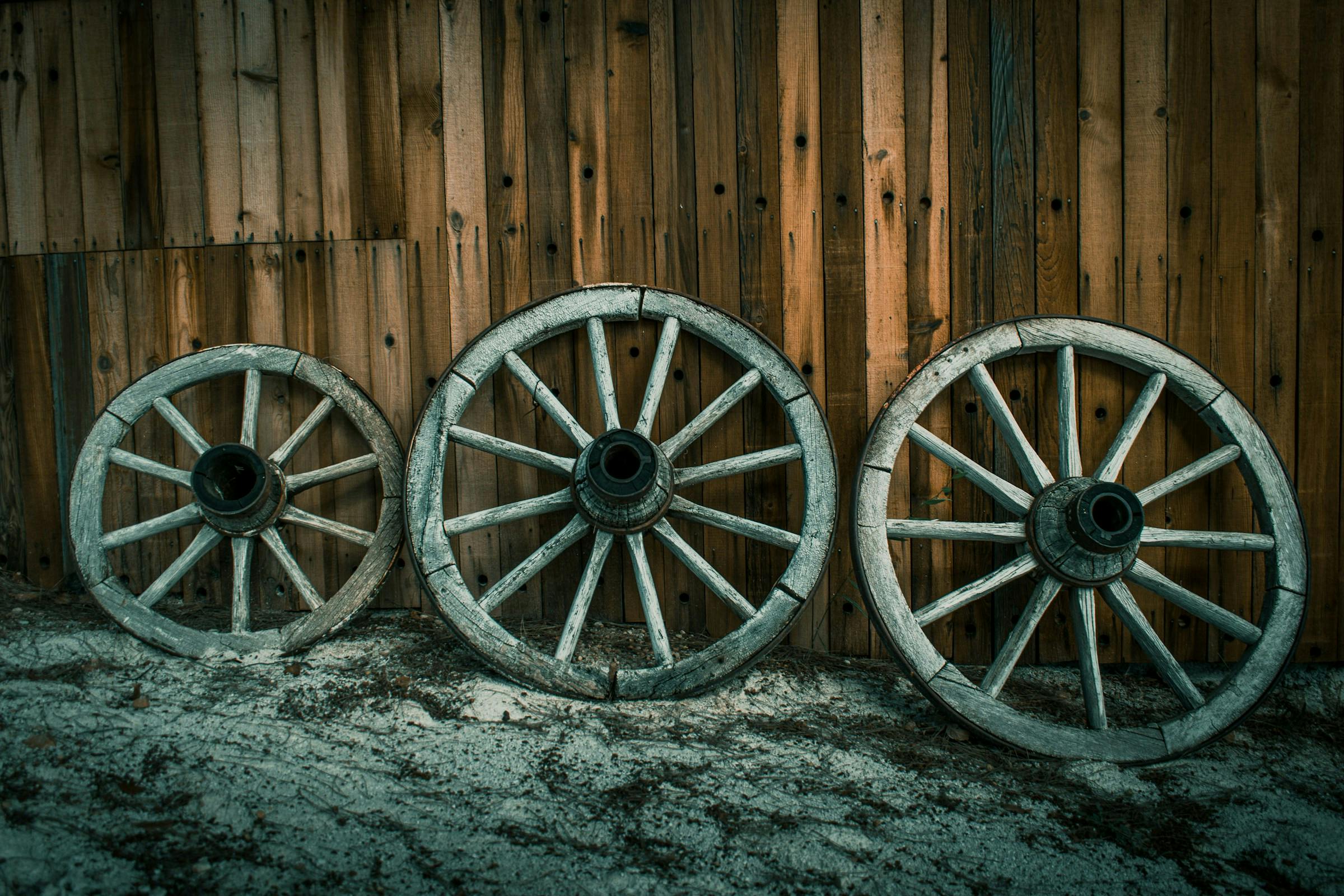 A photo of three worn, wooden wheels.