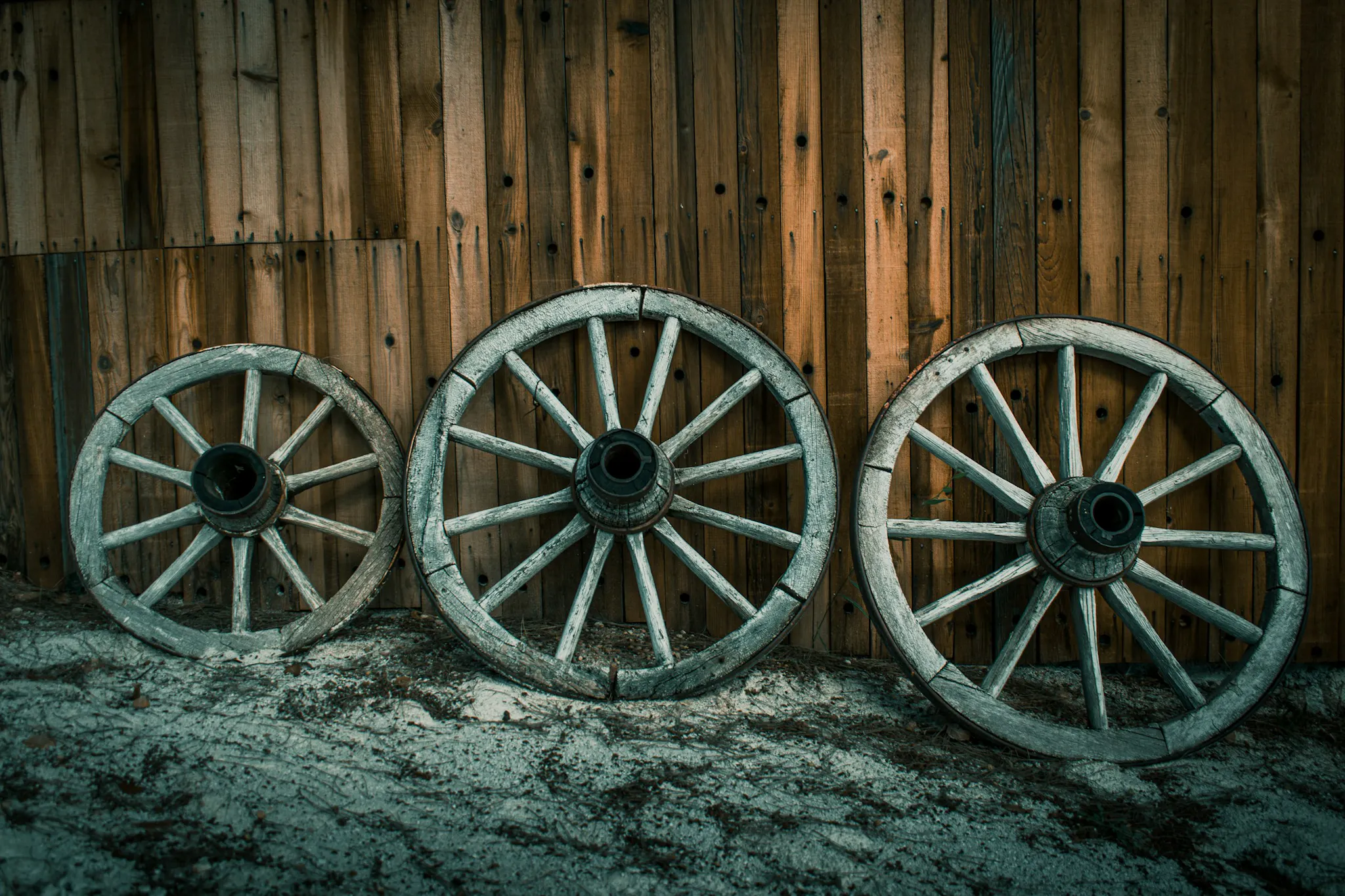 A photo of three worn, wooden wheels.
