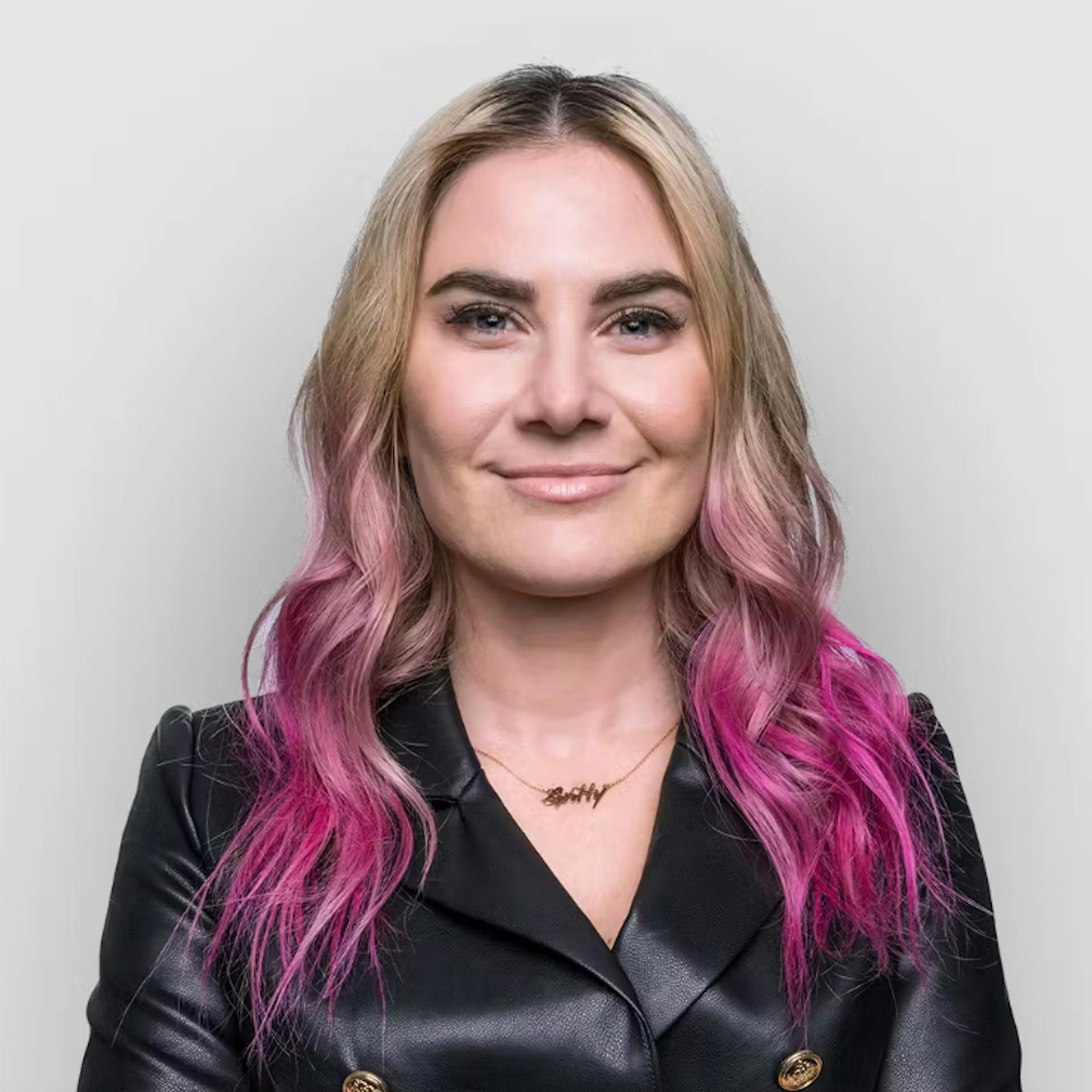 Headshot of Gritty In Pink marketplace founder Shira Yeving wearing a black lether jacket, smiling, against pale gray background.