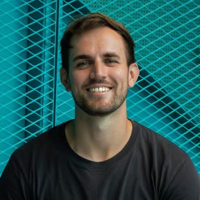 Headshot of socialbnb co-founder Alexander Haufschild in a black t-shirt, smiling, against a turquoise textured background.