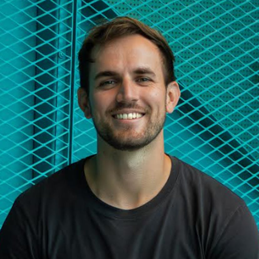 Headshot of socialbnb co-founder Alexander Haufschild in a black t-shirt, smiling, against a turquoise textured background.