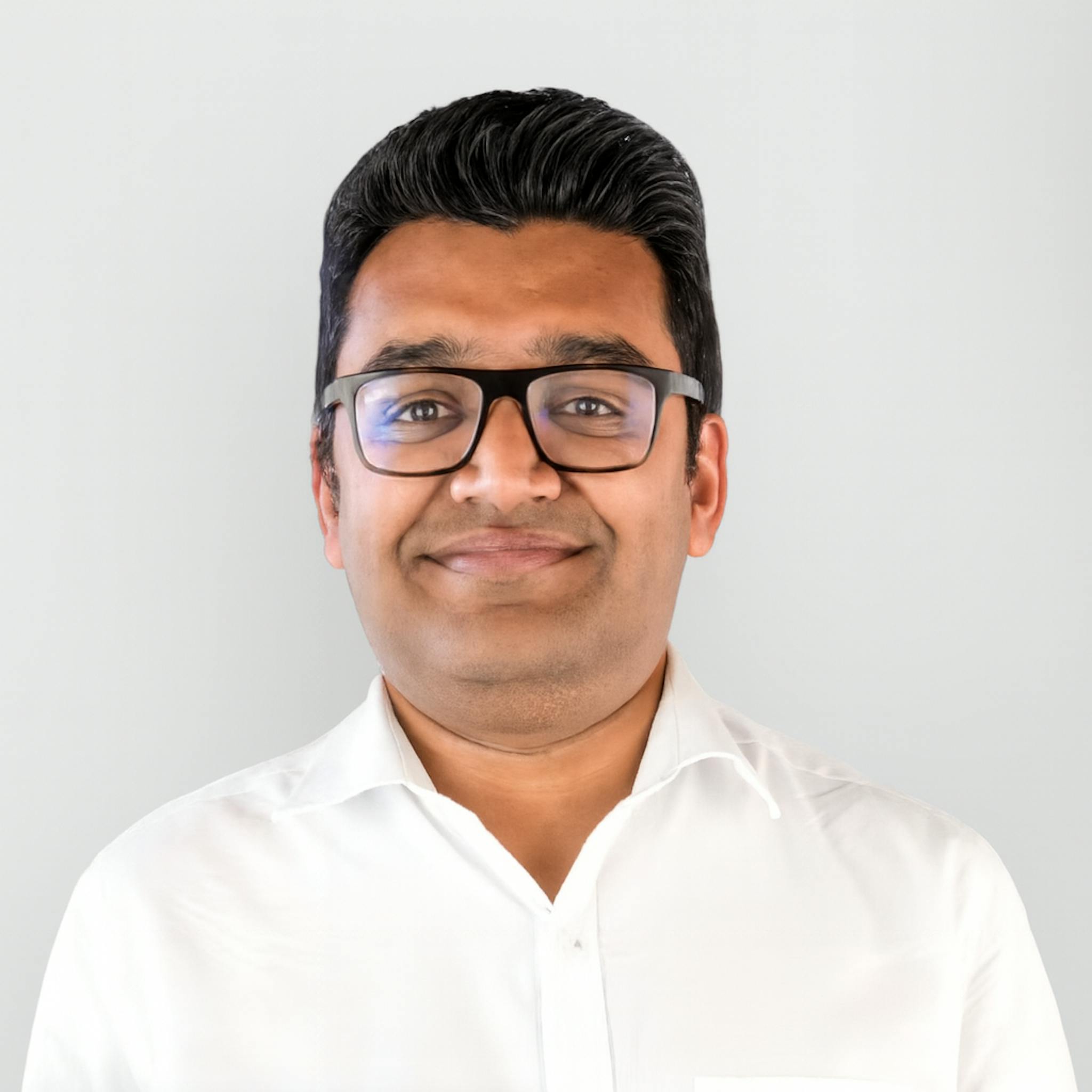 Headshot of Drive lah co-founder Gaurav Singhal wearing a white shirt, similing, against a pale gray background.