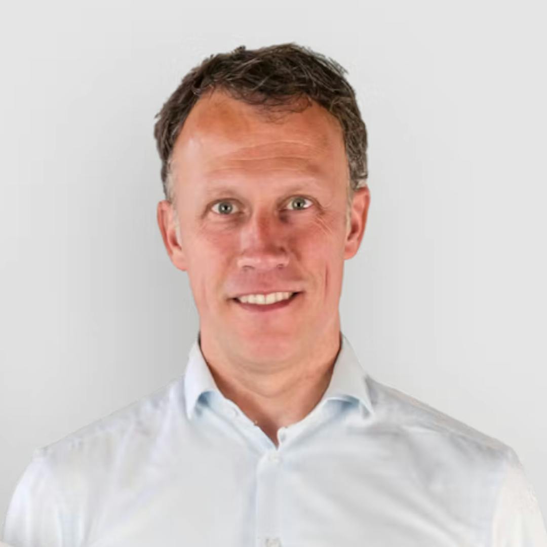 Headshot of Drive lah co-founder Dirk-Jan der Horst wearing a pale blue shirt, similing, against a pale gray background.