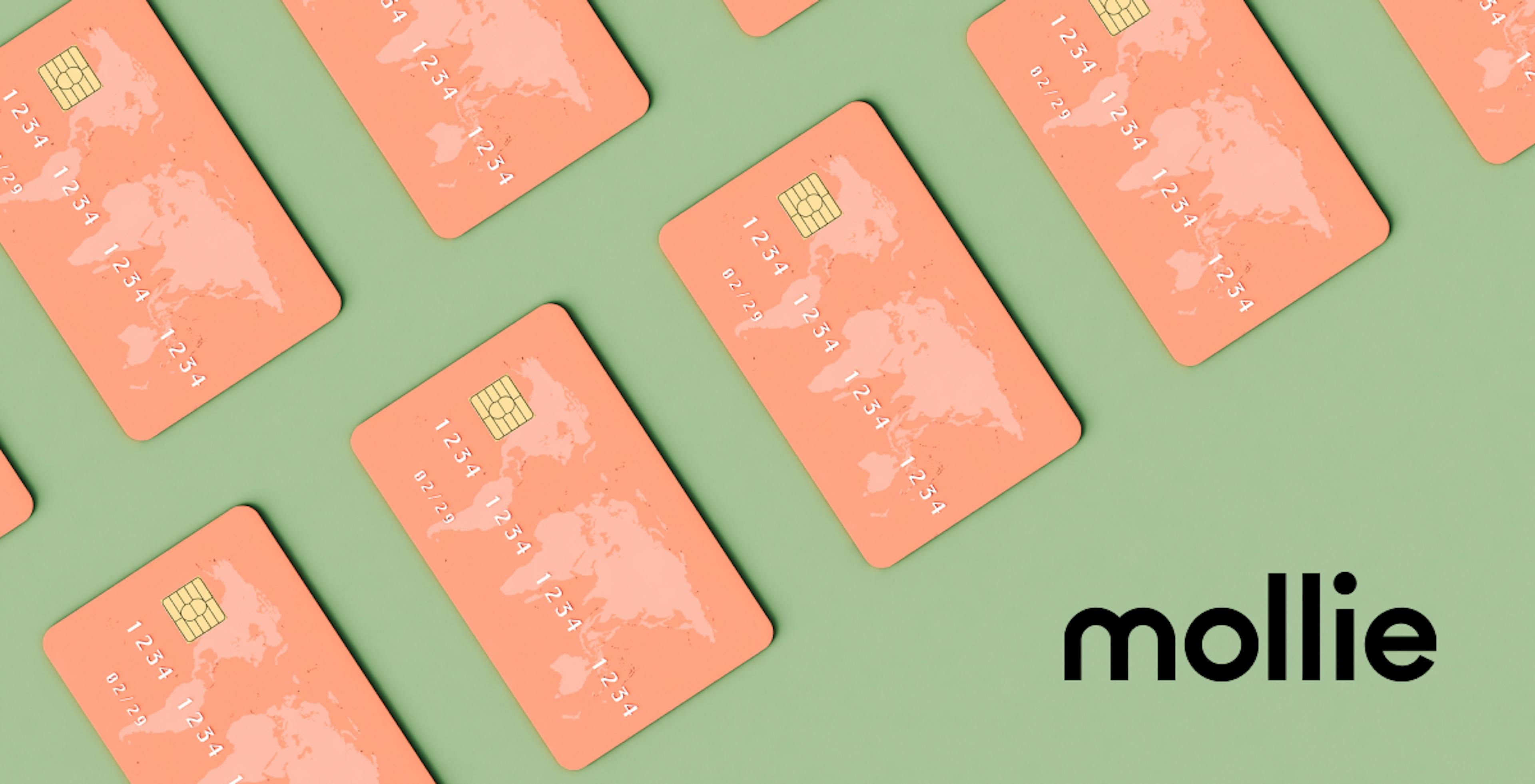 Sage green background with salmon pink credit cards with world map on the upper left corner, black Mollie logo in bottom right corner.