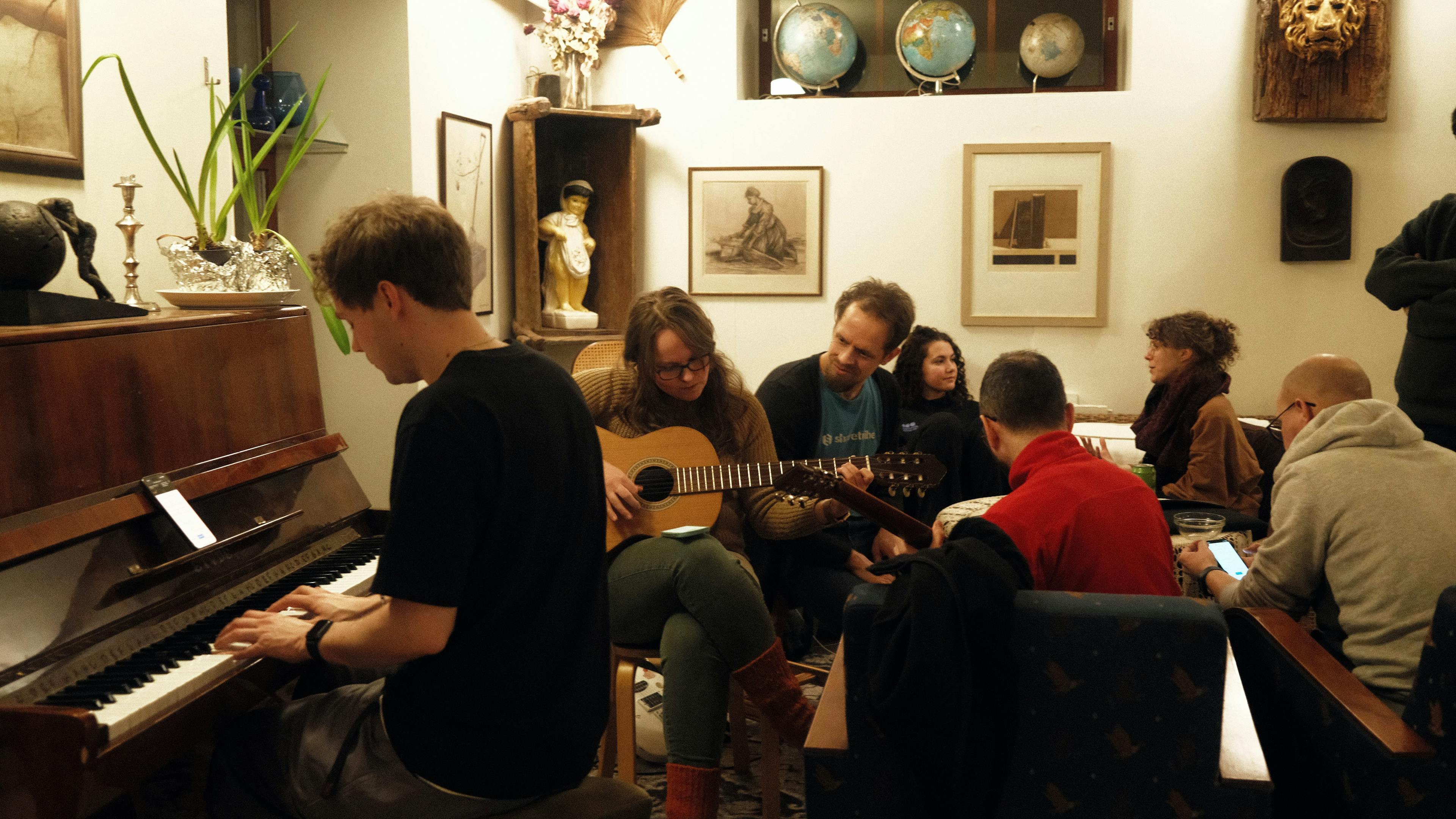 People gathered in a cozy living room, playing piano and guitar together.