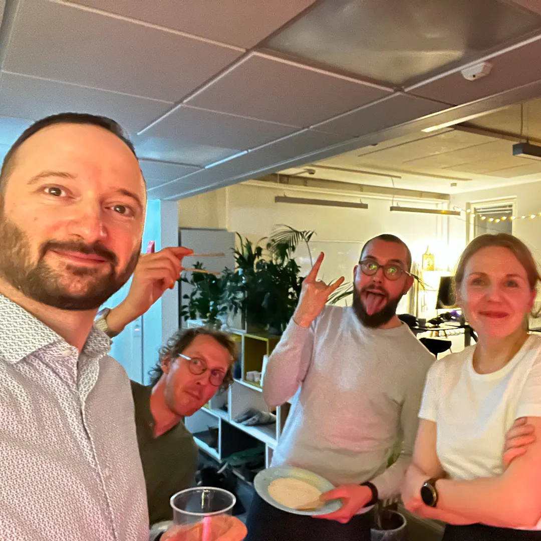 Boyan smiling and taking a selfie at a party with Mira gently smiling and Sjoerd and Thomas making funny faces.