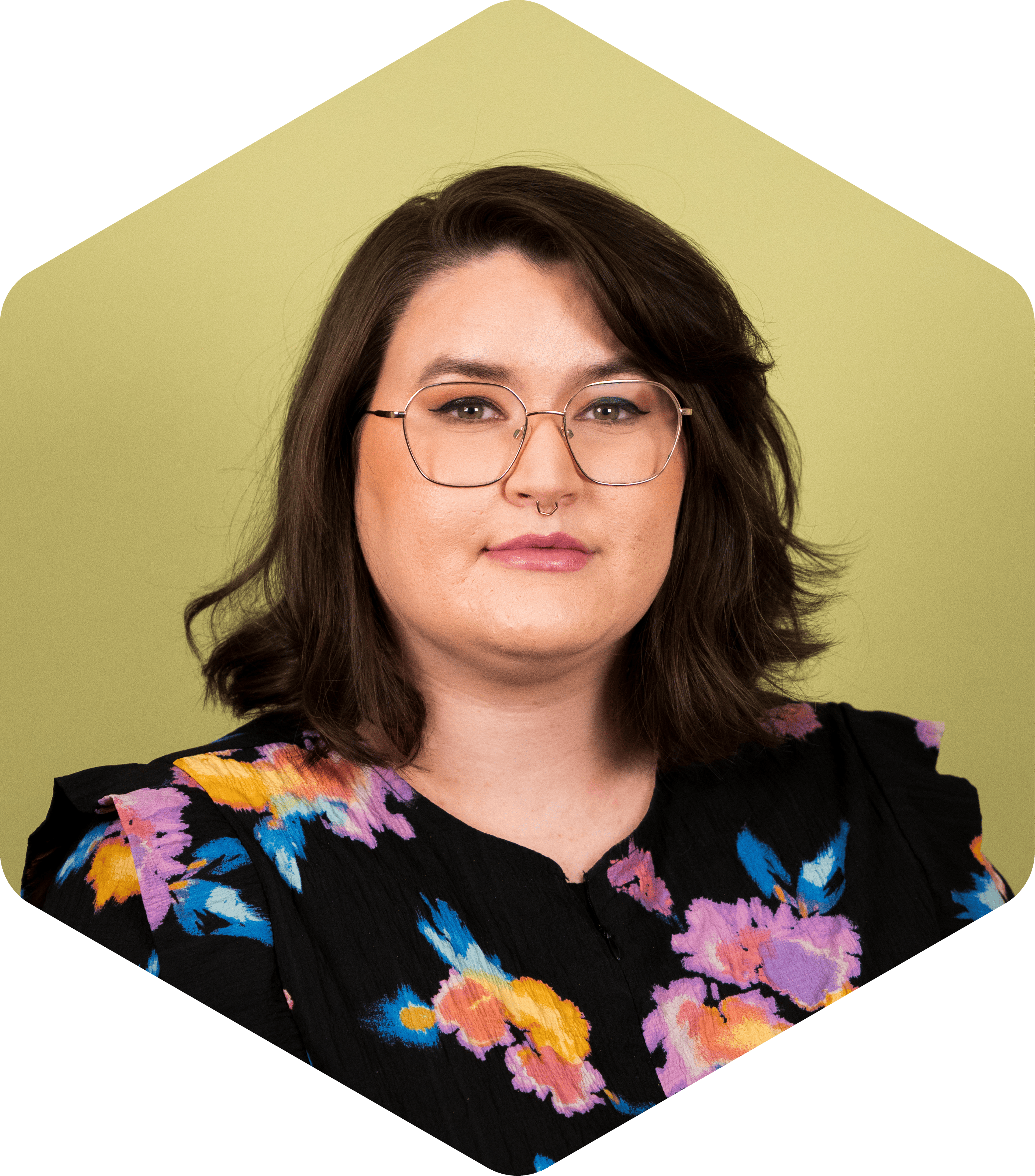 A headshot of Amanda wearing floral shirt on a green background, gently smiling at the camera. 