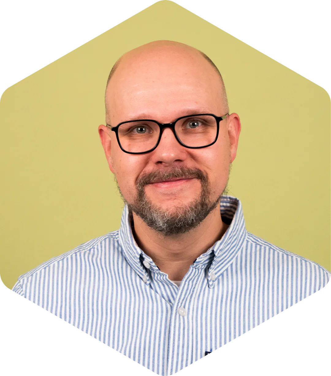 Mikko wearing glasses and a striped button-down shirt on a light green background.