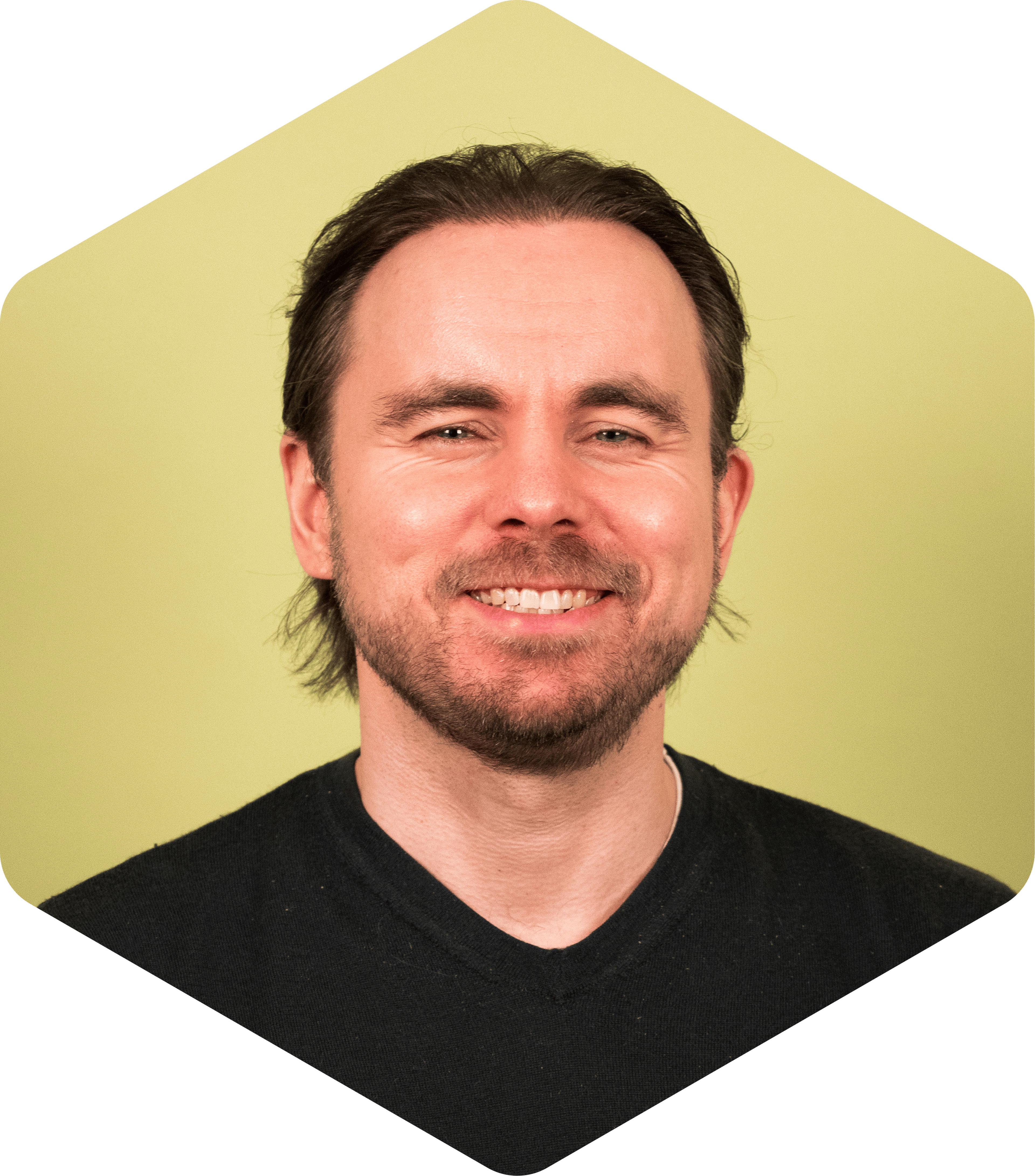 Portrait of Vesa smiling gently at the camera, wearing a black shirt on a light green background.