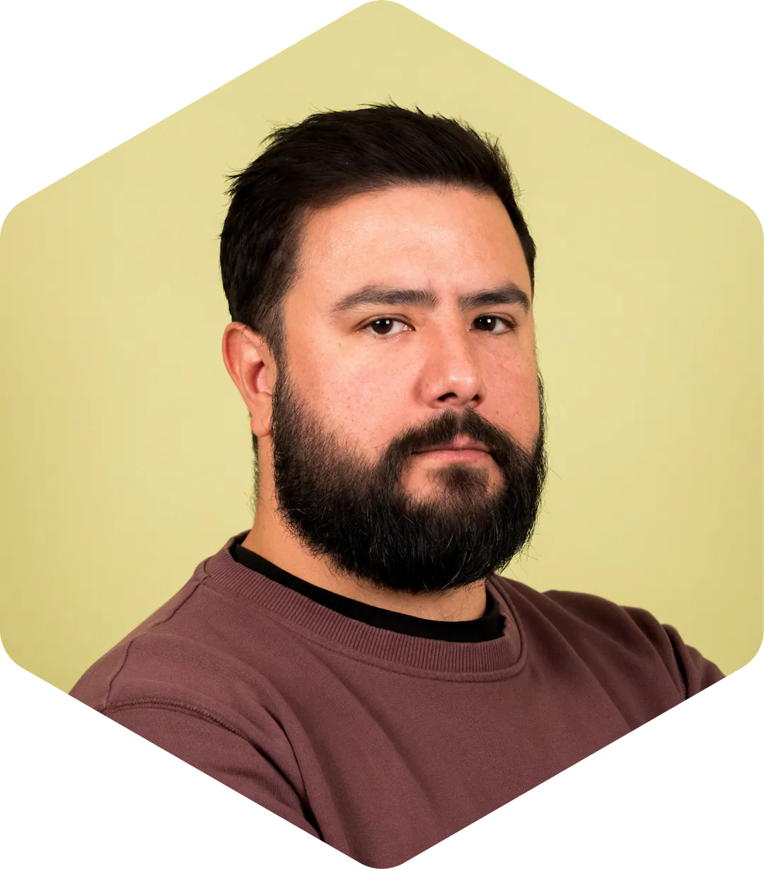 Luis facing the camera, wearing a mauve sweatshirt on a light green background