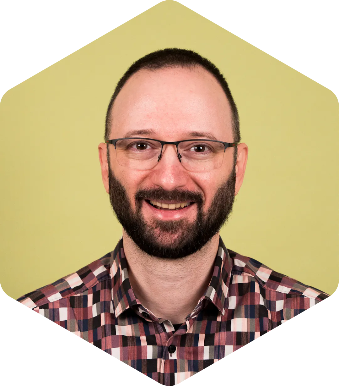 Boyan smiling, wearing a patterned shirt on a light green background.