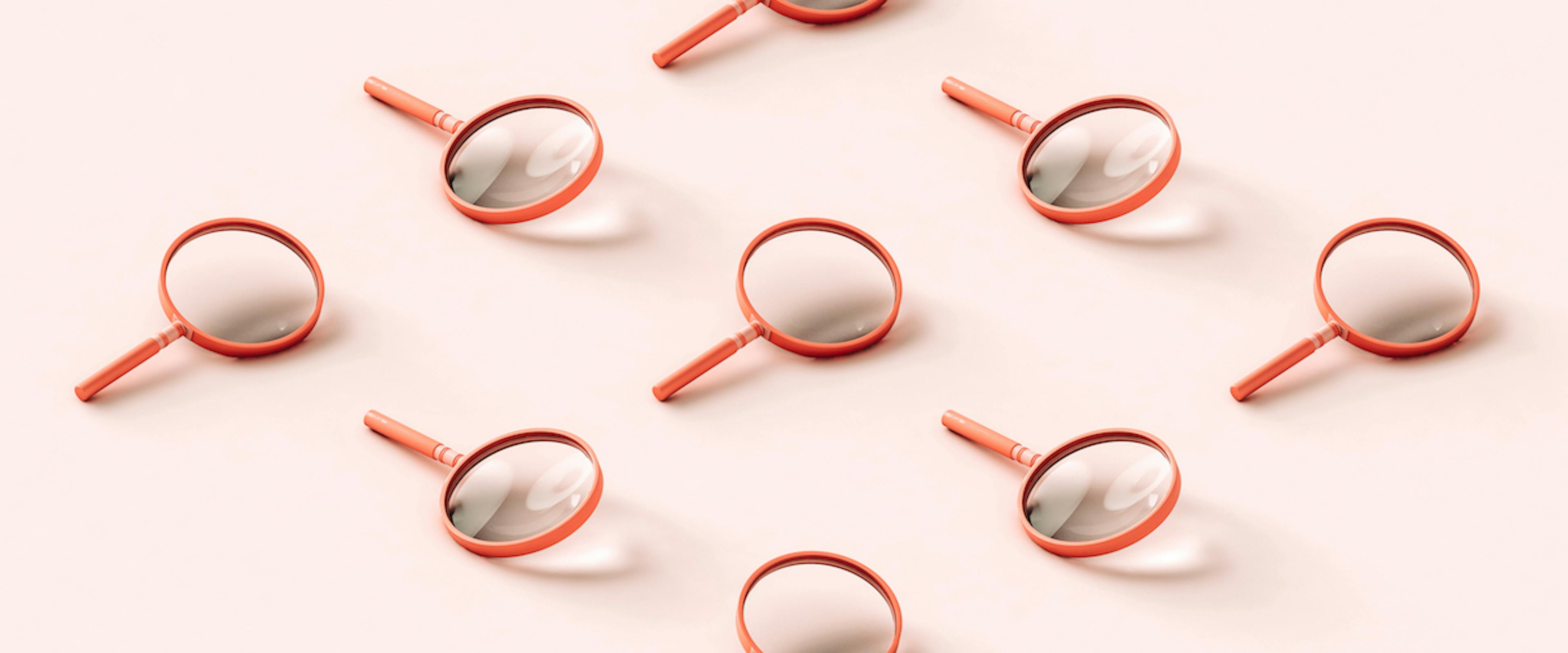 Nine pink 3D magnifying glasses arranged in a reclining diamond shape on pale pink background.