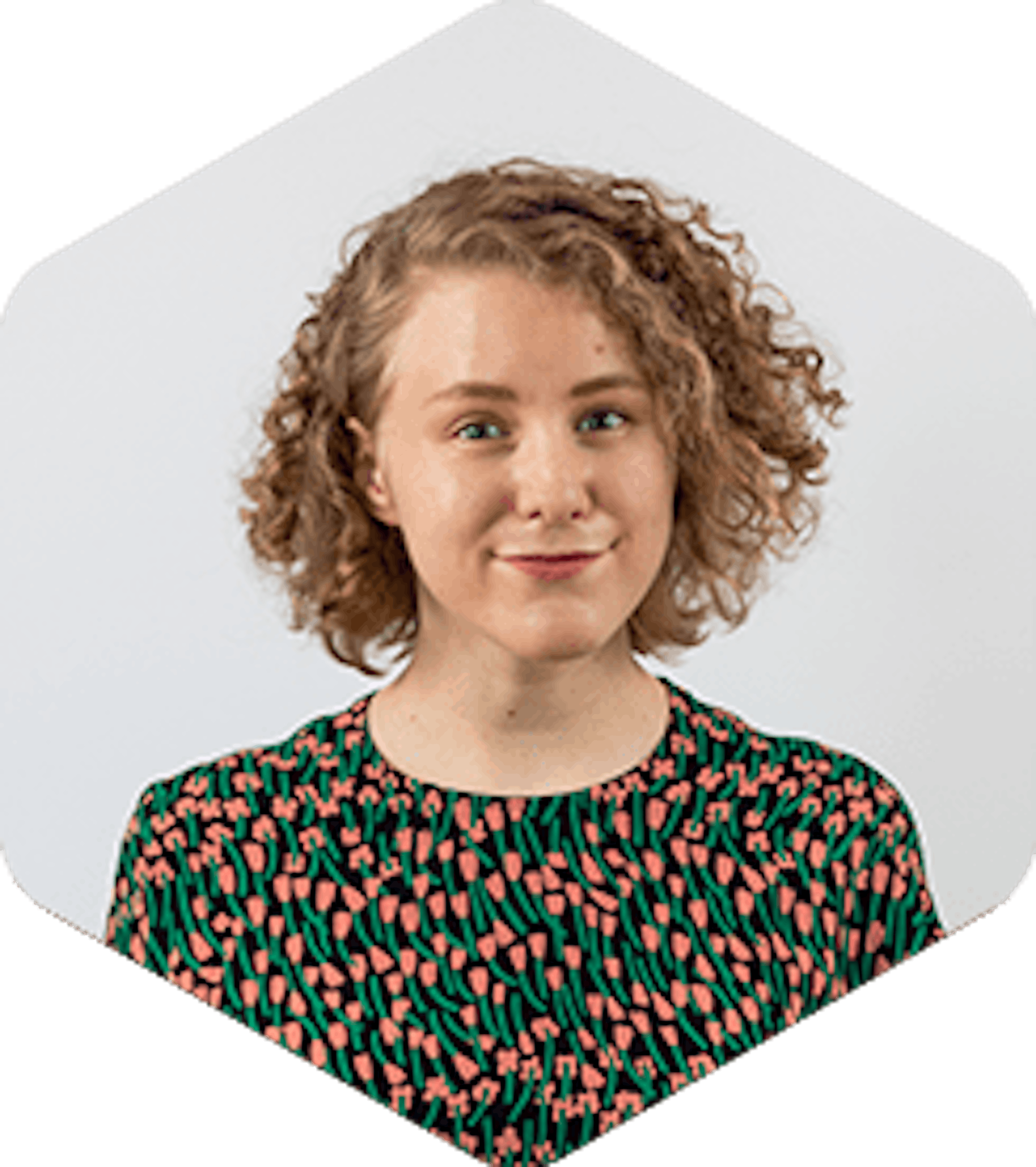 Katri is white woman with curly dark blonde hair. She's wearing a shirt with salmon pink and green flowers.