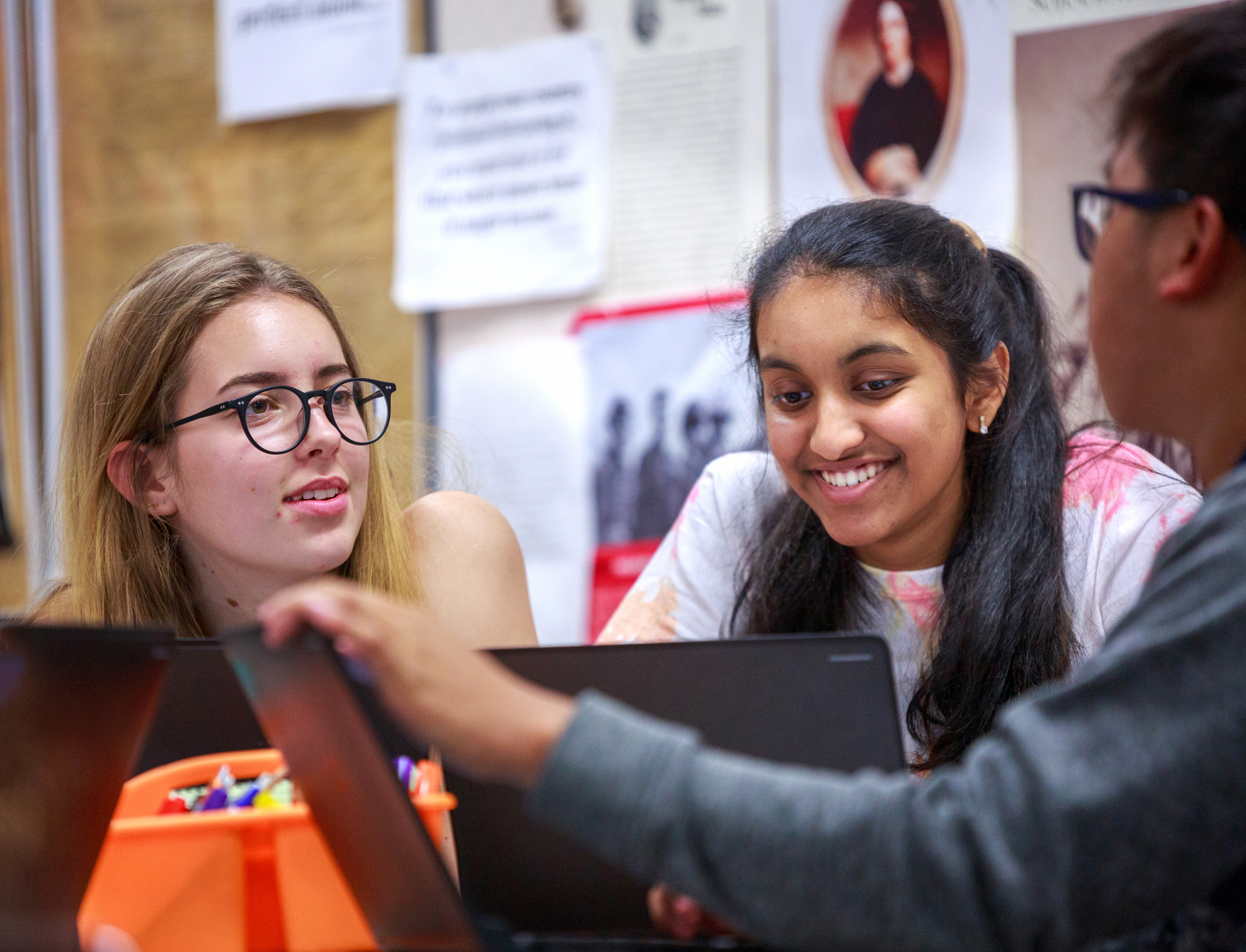 Three high school students working on laptops 