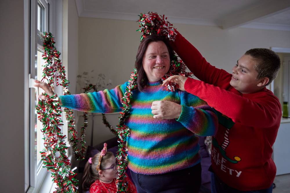A woman and child smiling at home playing with tinsel