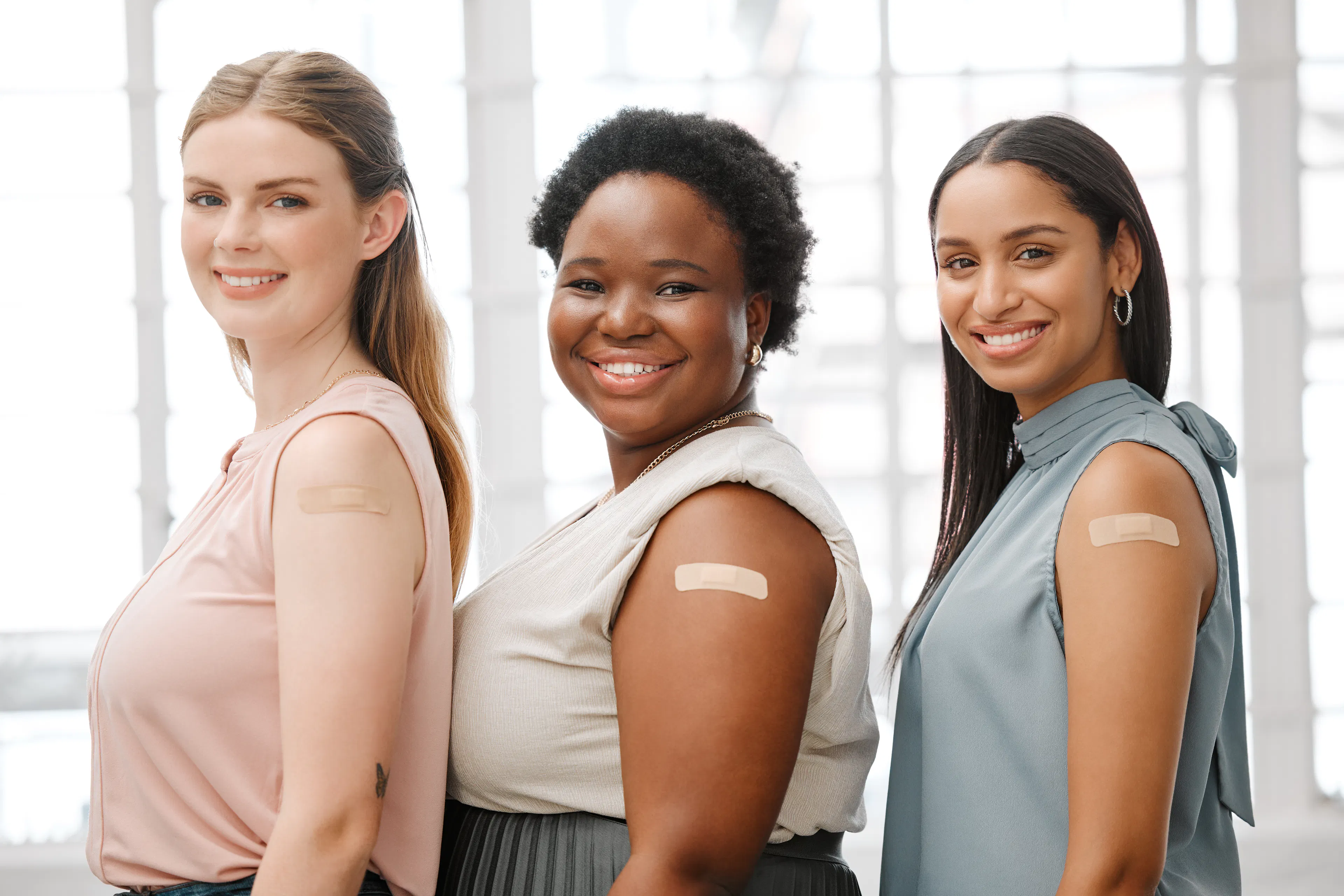 smiling women after receiving vaccination with plasters on arm