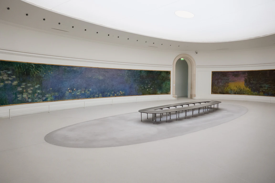 흰 타원형 방의 벽을 따라 Monet 의 수련 대작이 빙 둘러 걸려 있는 Musée de l'Orangerie 의 전시실