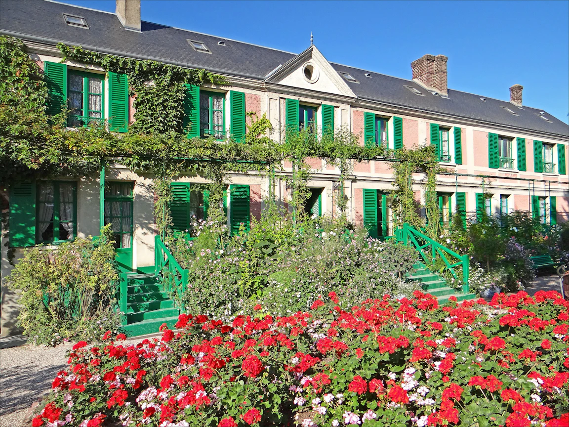 초록 덧창이 달린 분홍빛 긴 집 앞에 붉은 꽃이 가득 핀 Giverny 의 Monet 집