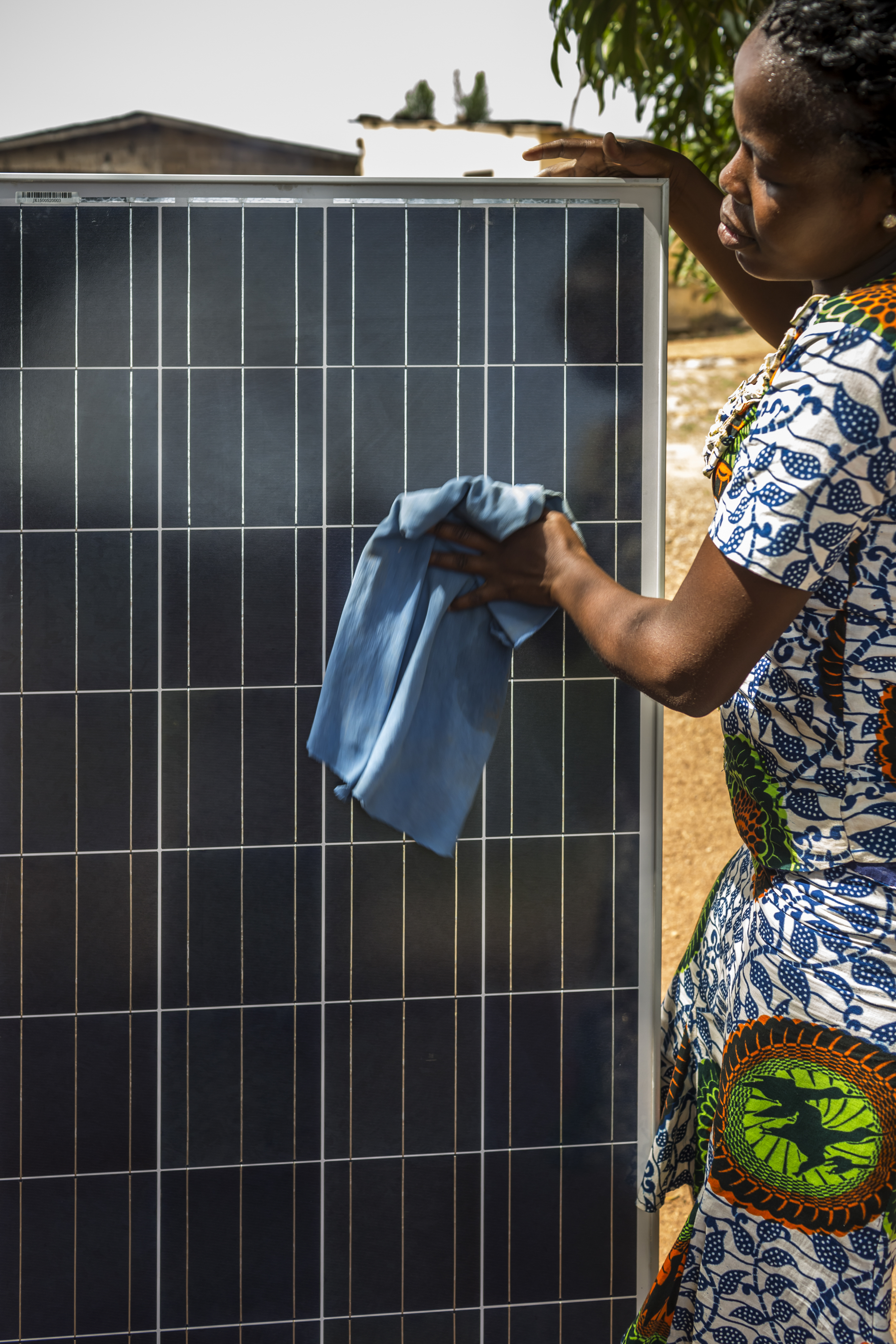 A lady cleans a solar panel with a rag
