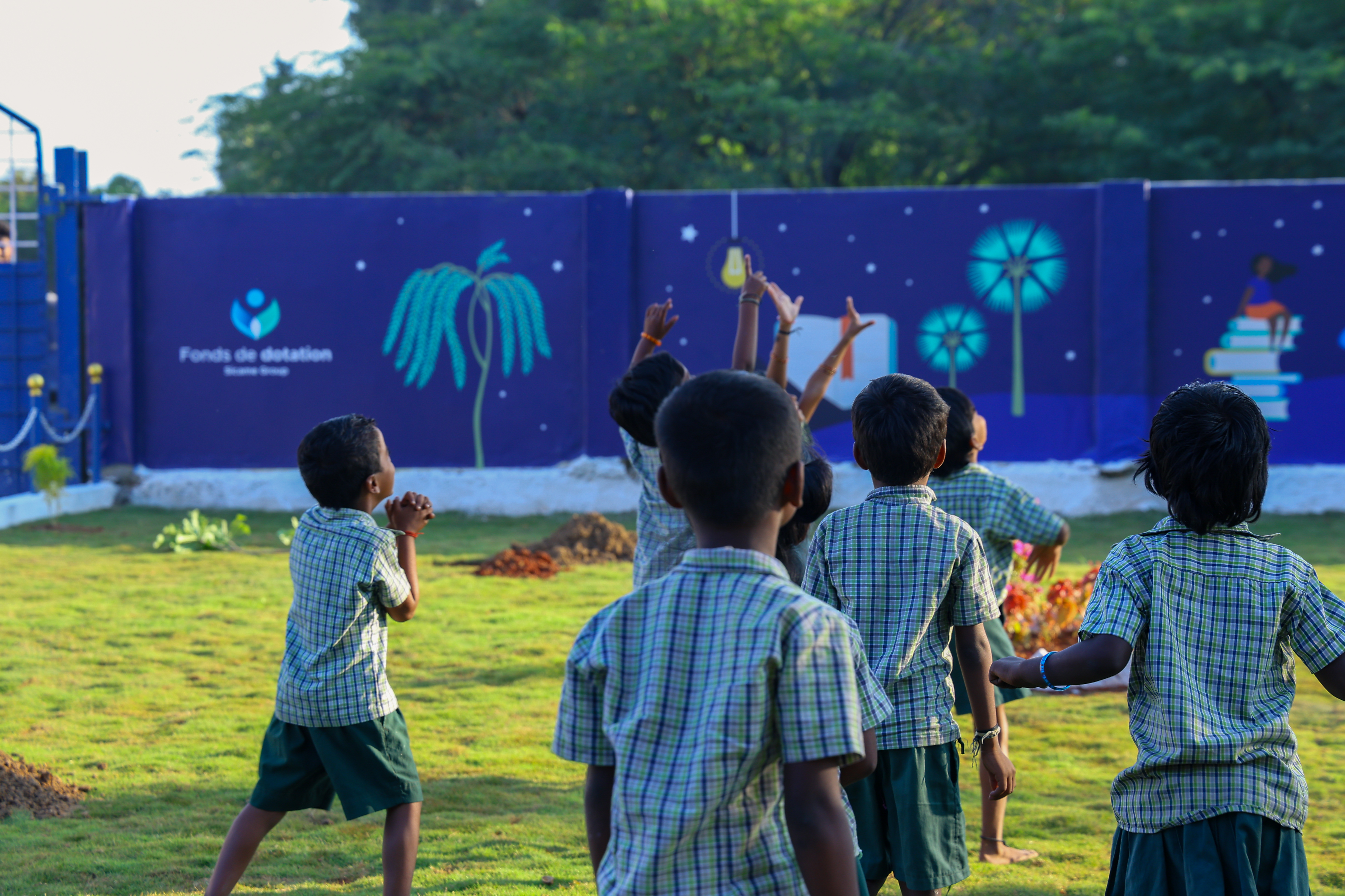 Indian children in school uniform outside, walking in the grass and celebrating