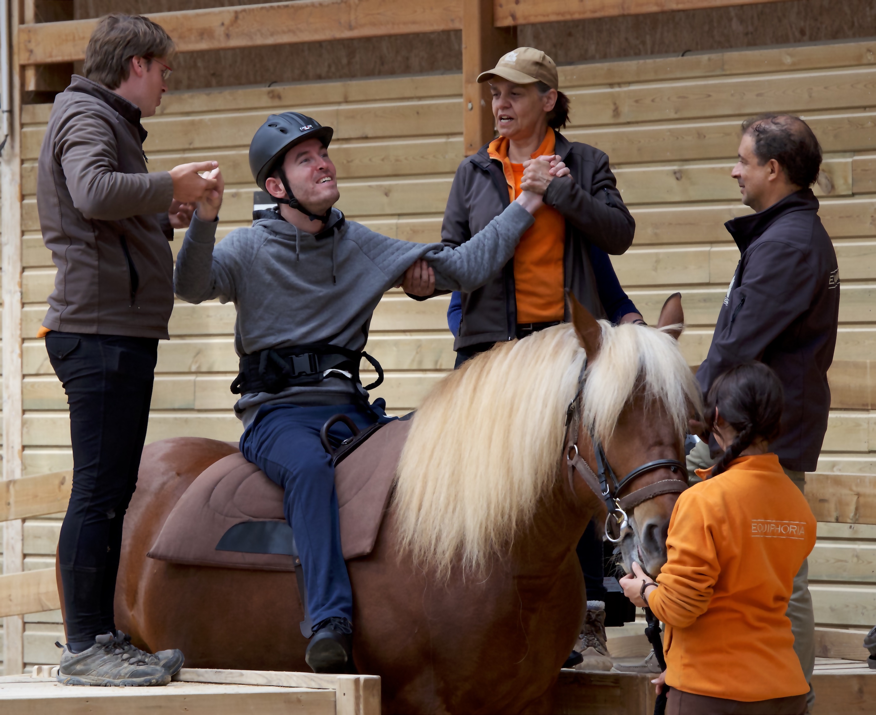 2 Équiphoria employees hold the hands of a disabled adult sitting on a horse
