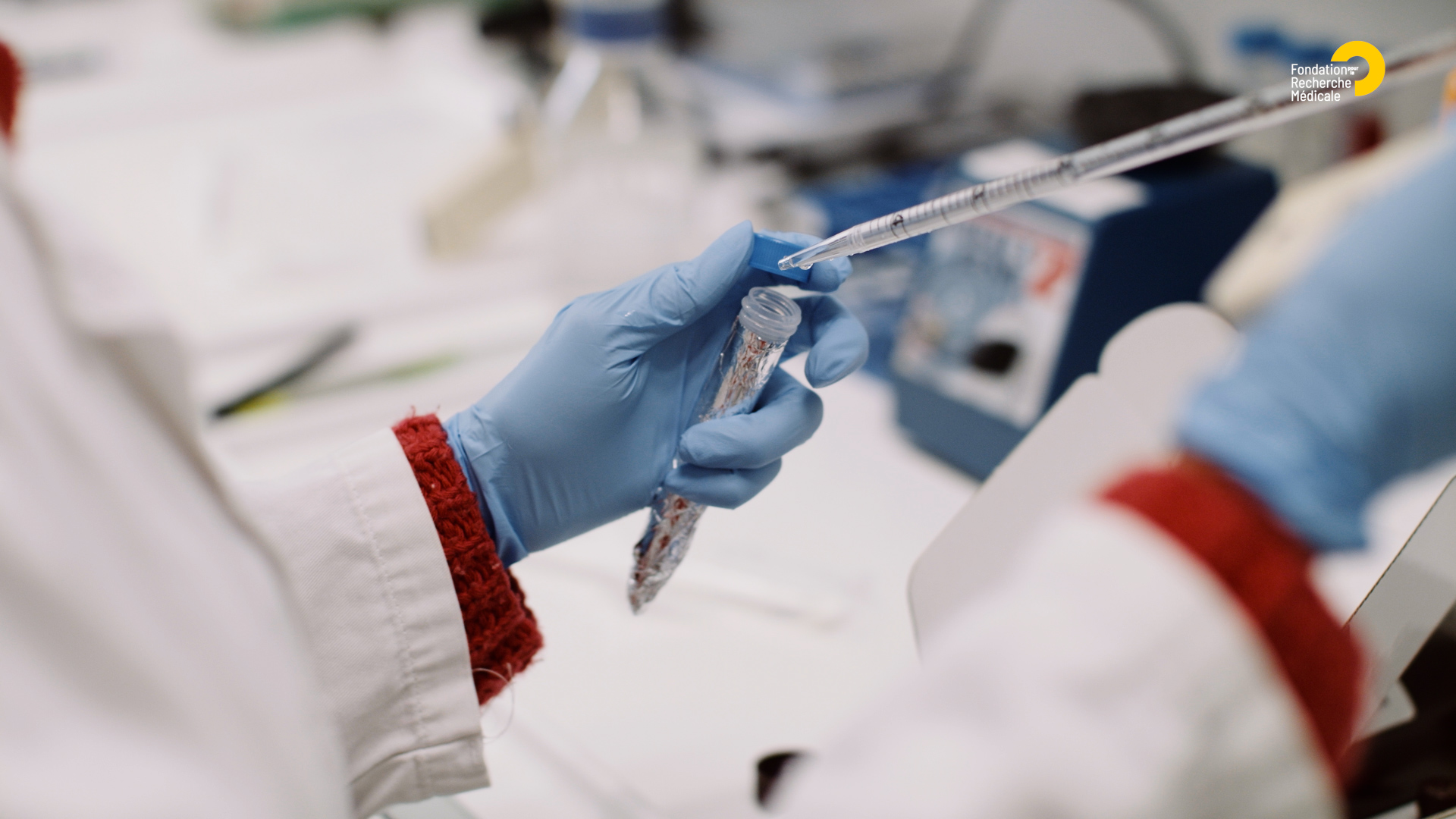 Gloved hands of a scientist holding a pipette