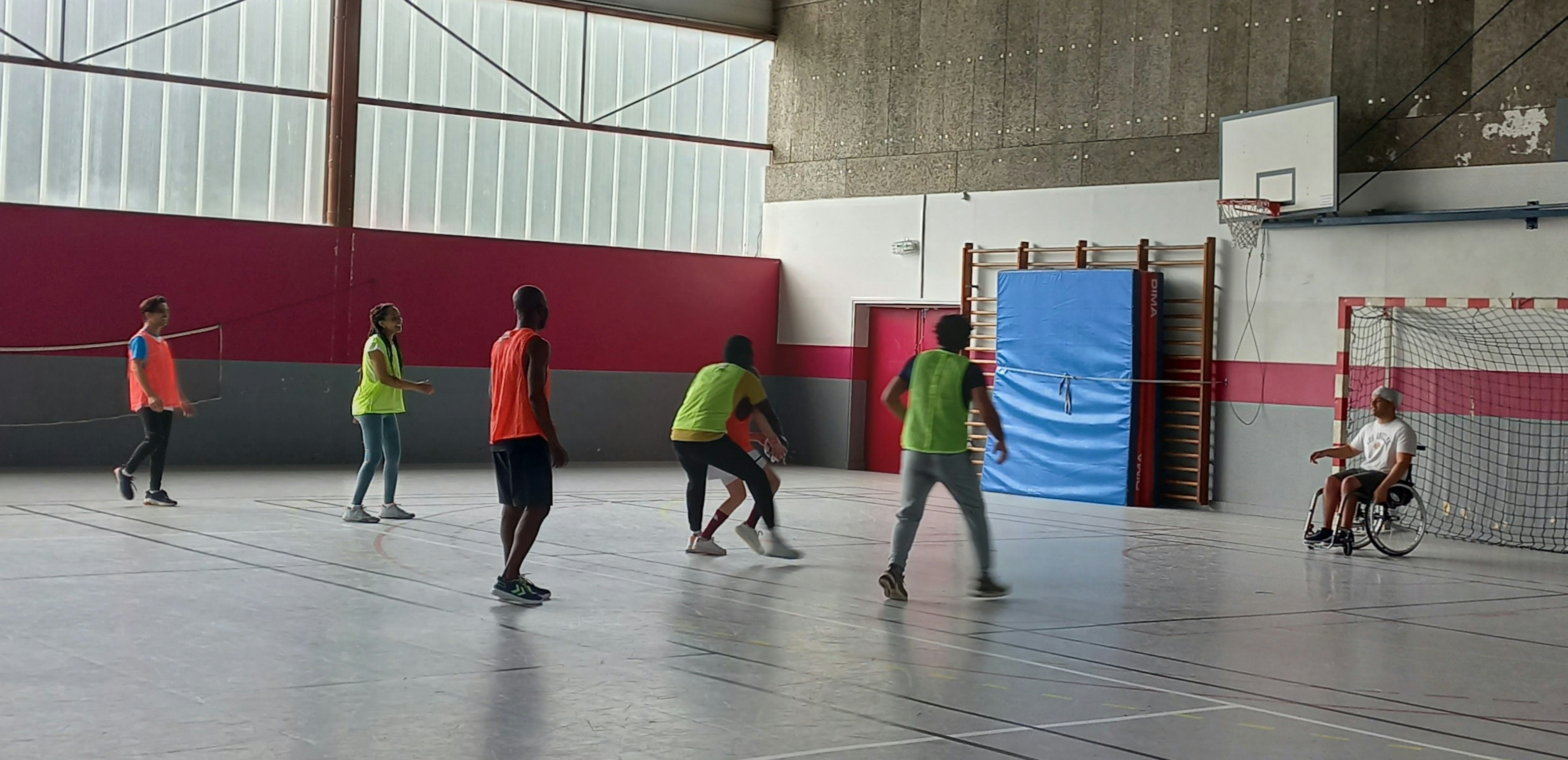Un grupo de personas practica un deporte de equipo bajo techo con un portero en silla de ruedas