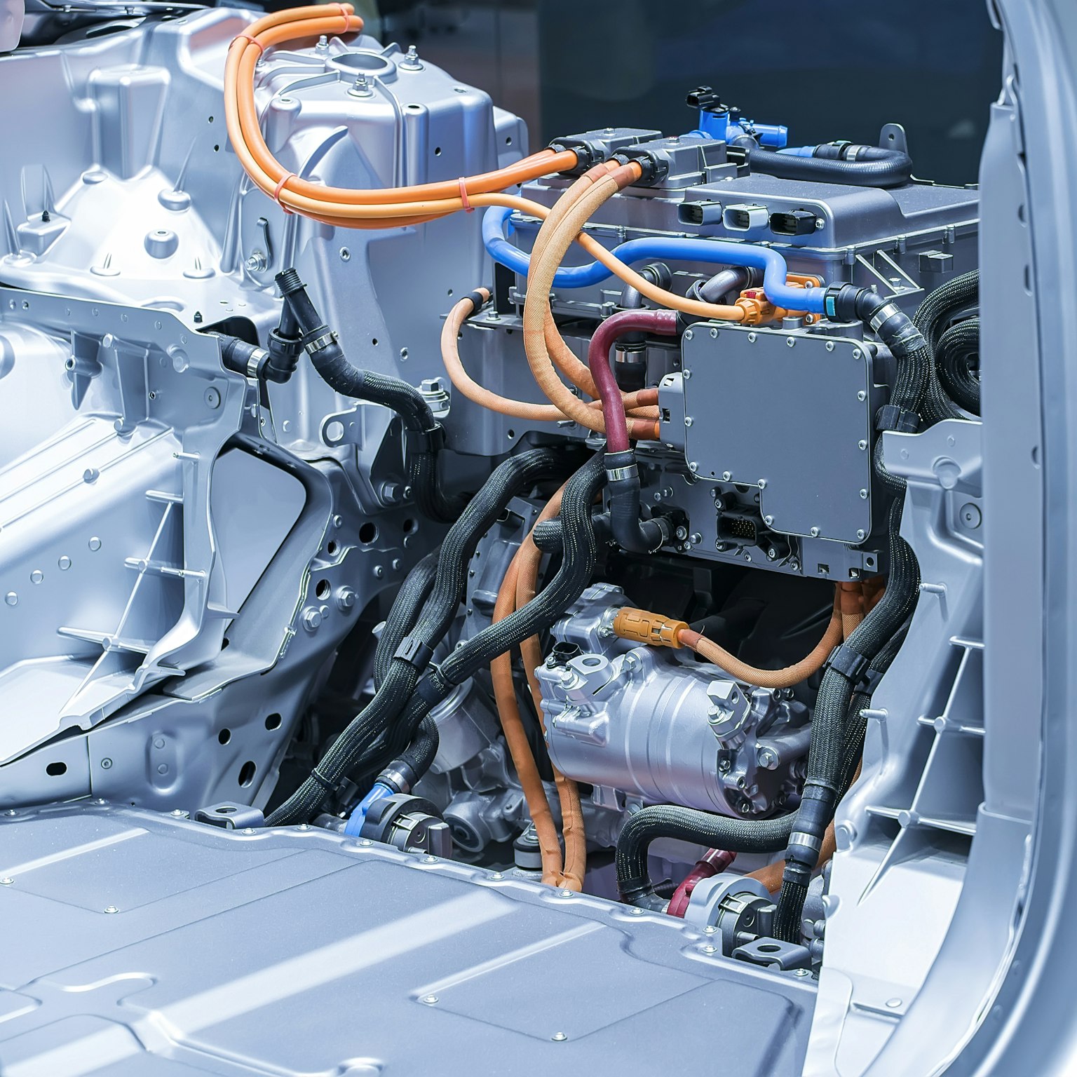 Acercamiento de una parte de un coche en construcción, mostrando diferentes elementos conectados por cables o juntas