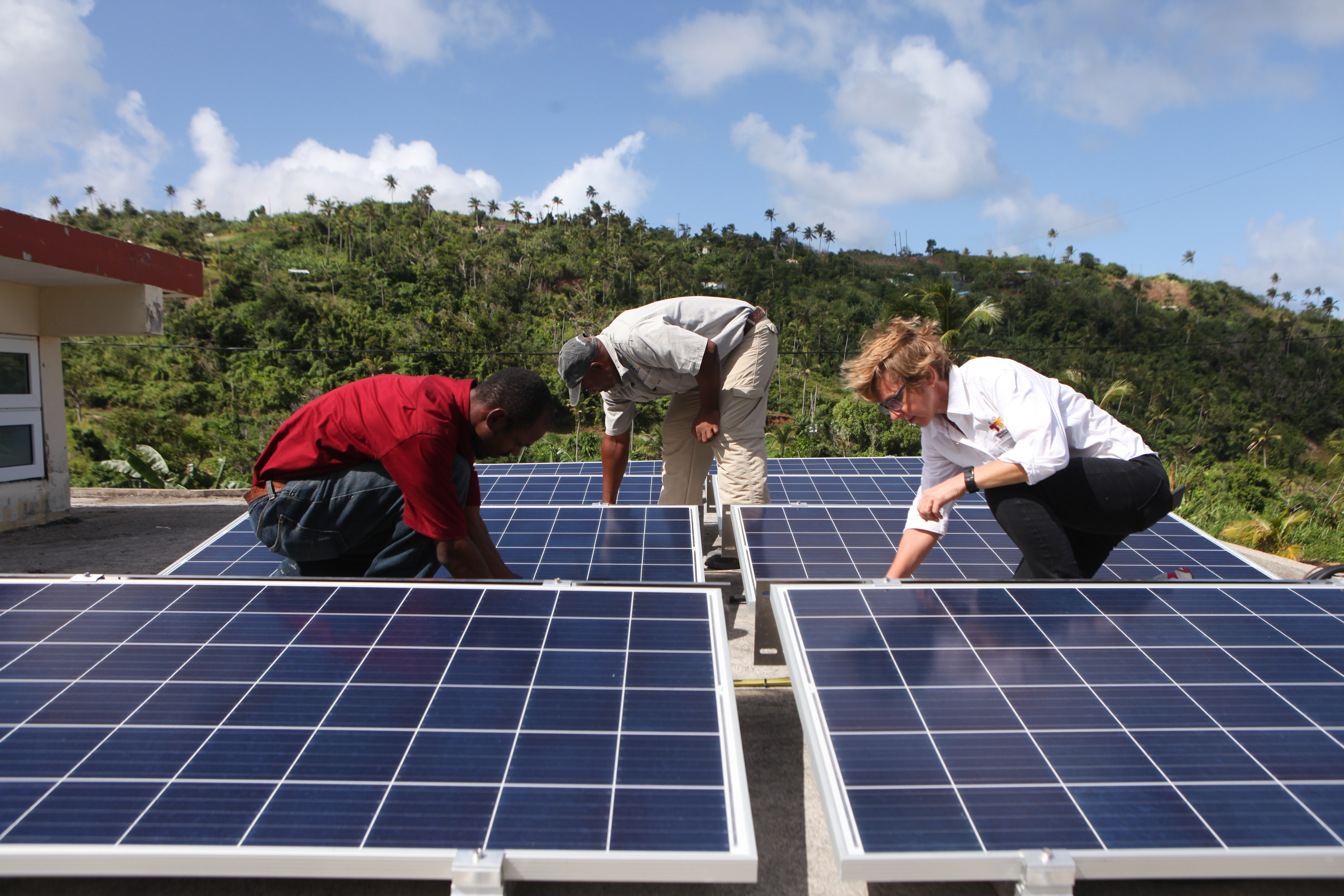 3 people working among solar panels