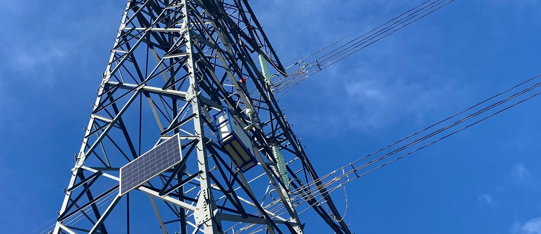Transmission tower in front of a blue sky, with monitoring accessories