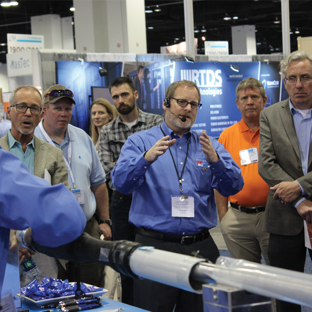 Groupe de personnes sur un stand lors d'un salon professionnel, l'homme au milieu explique aux clients
