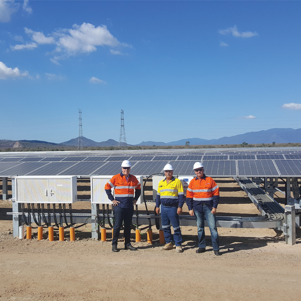 3 hommes debout en tenue de chantier devant une ferme solaire en Australie
