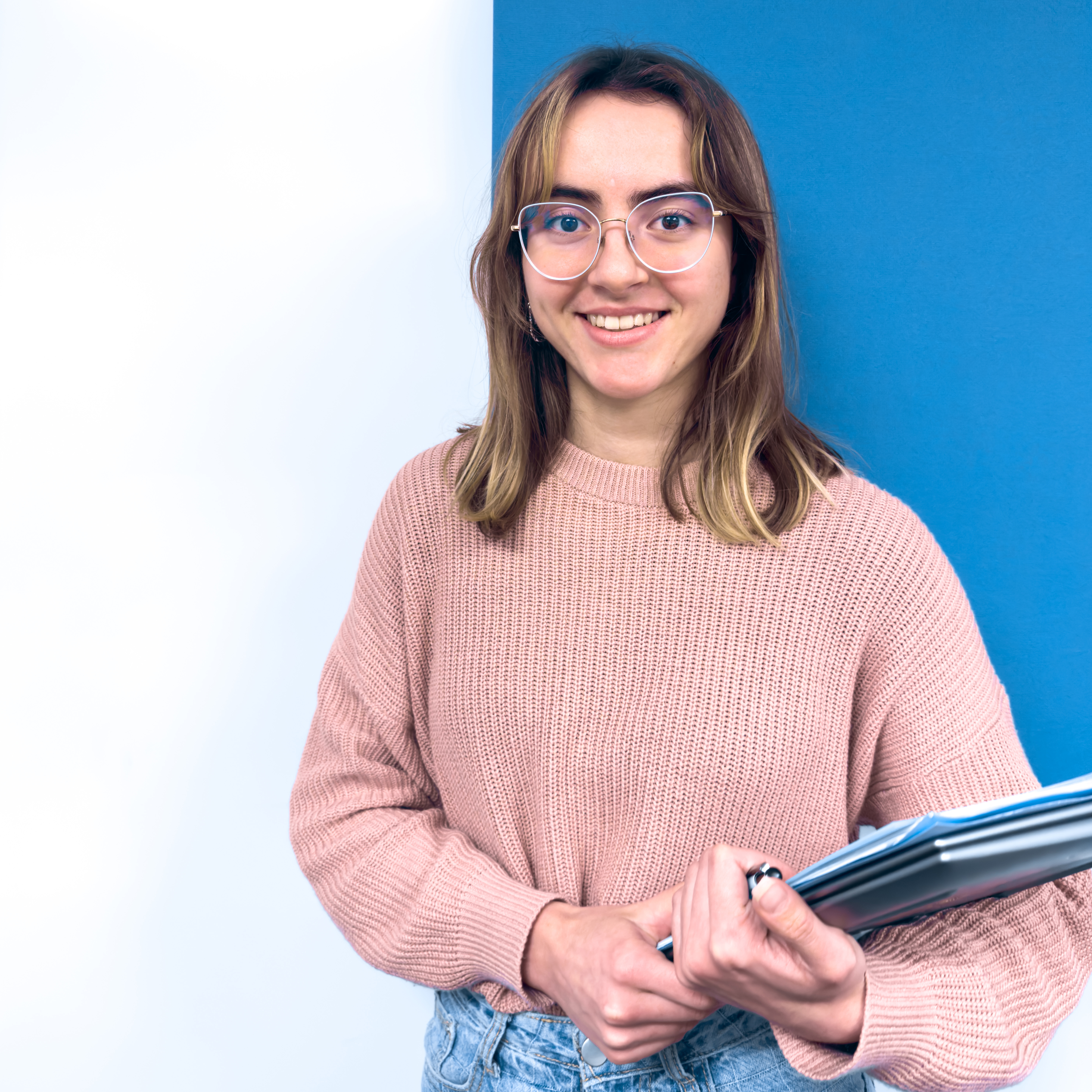 Student, smiling, carrying files and a laptop