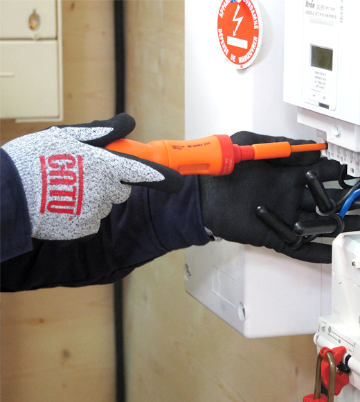 Catu safety glove holding an insulated screwdriver, working on an electrical box