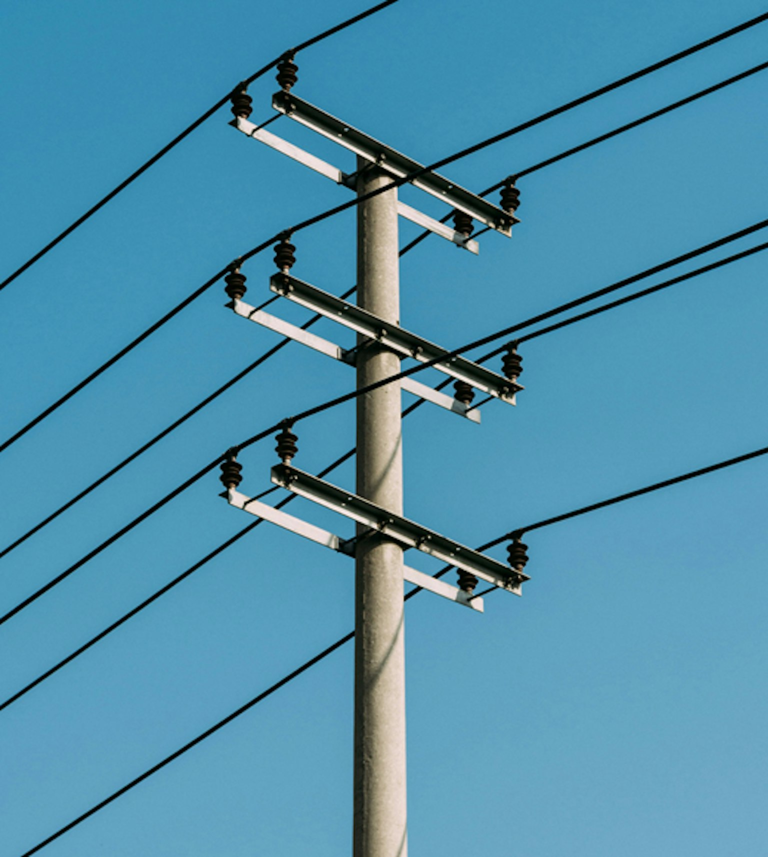 Poteau de distribution électrique devant ciel bleu